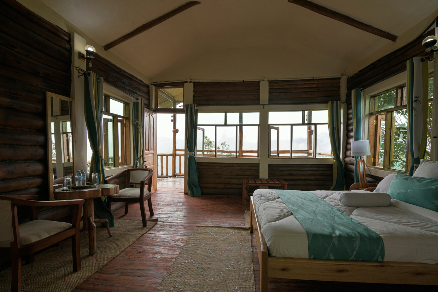 Spacious eco-luxury guest suite with panoramic forest and Virunga Mountain views at Orugano Bwindi Lodge