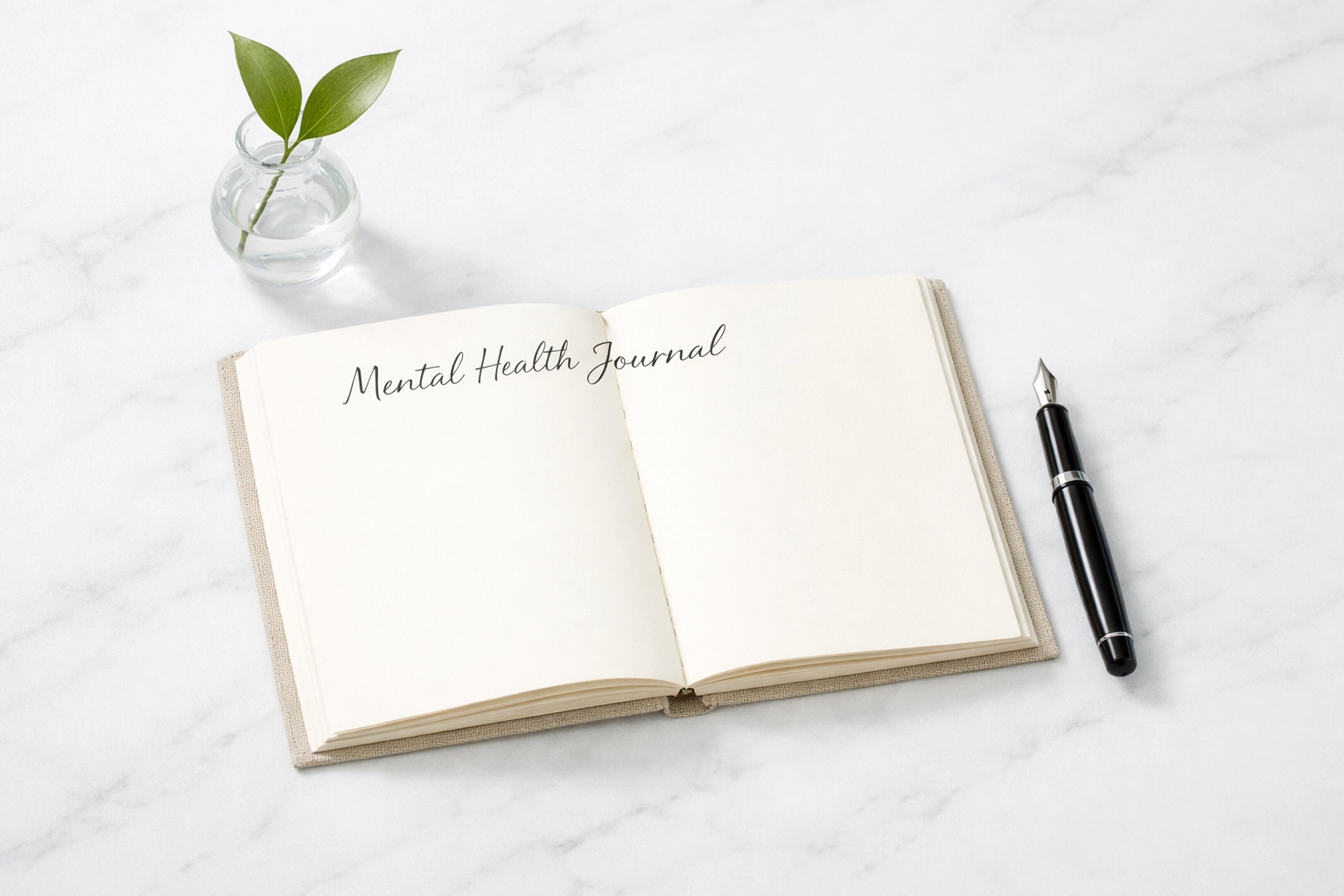 A journal and pen on a white table, symbolizing the clarity gained by tracking mental health for self-awareness.