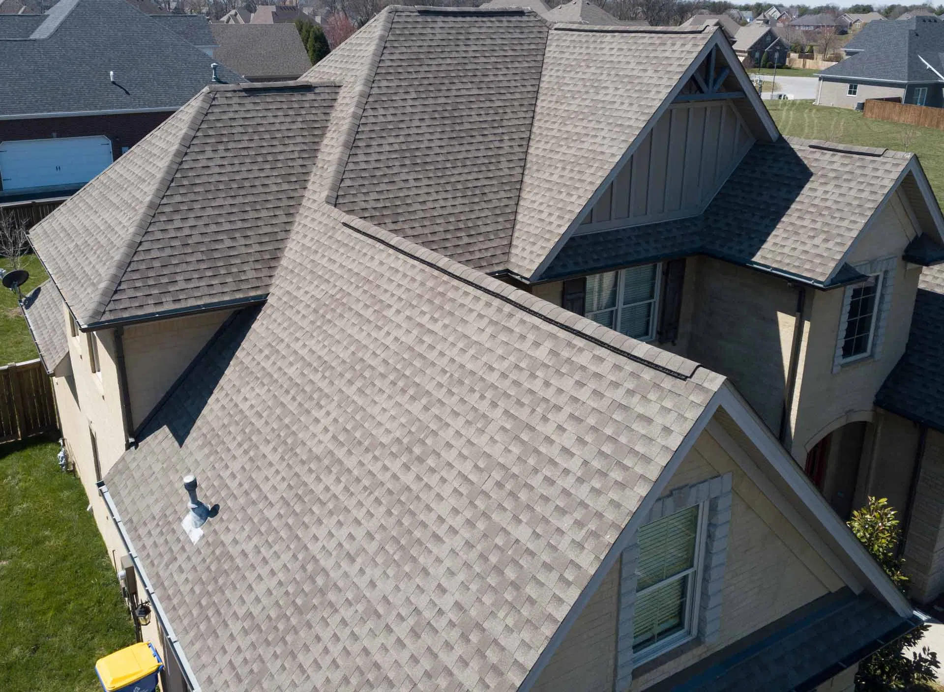 Aerial view of a residential home featuring a newly installed, high-quality asphalt shingle roof