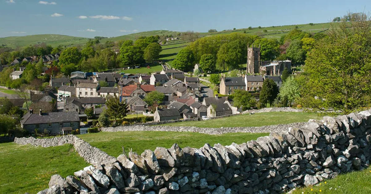 Peak District village panorama with rolling hills, stone buildings, and classic Derbyshire scenery.
