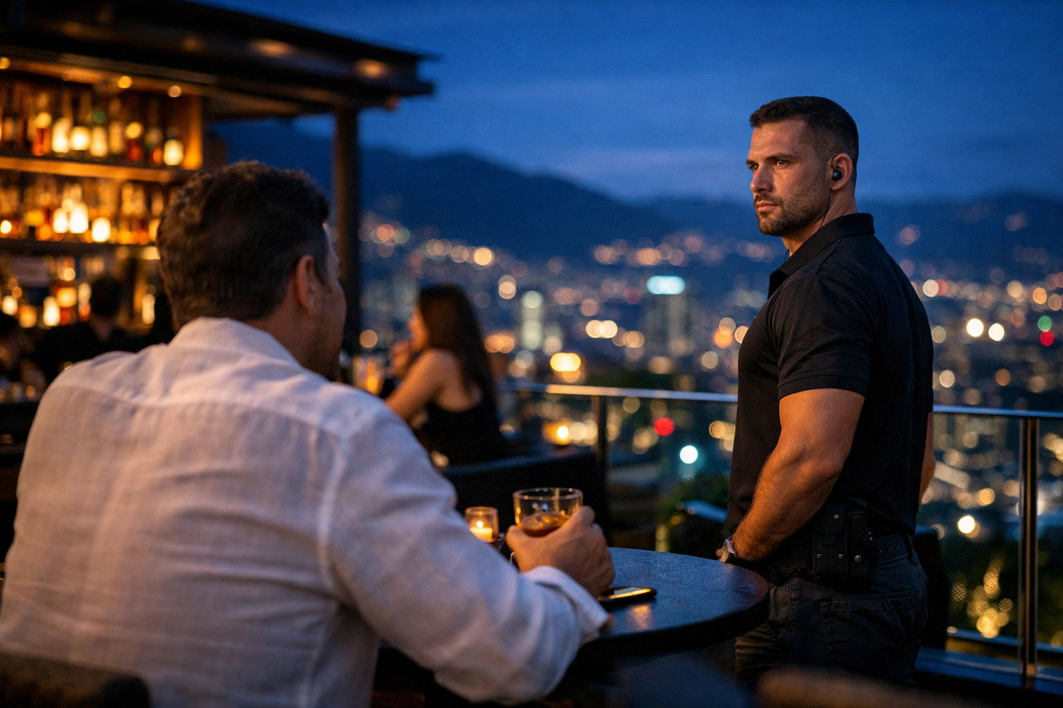 Discreet executive protection in Medellin showing a shadow guard monitoring a high-end rooftop lounge for client safety.
