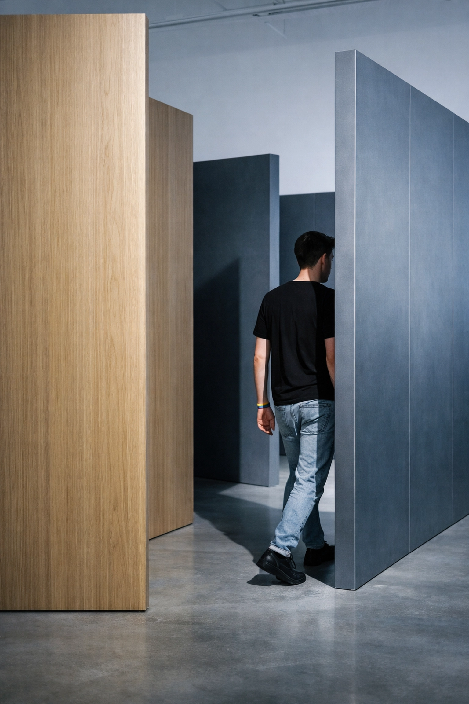 Gallery visitor navigating abstract partition installation reflecting queer spatial experience