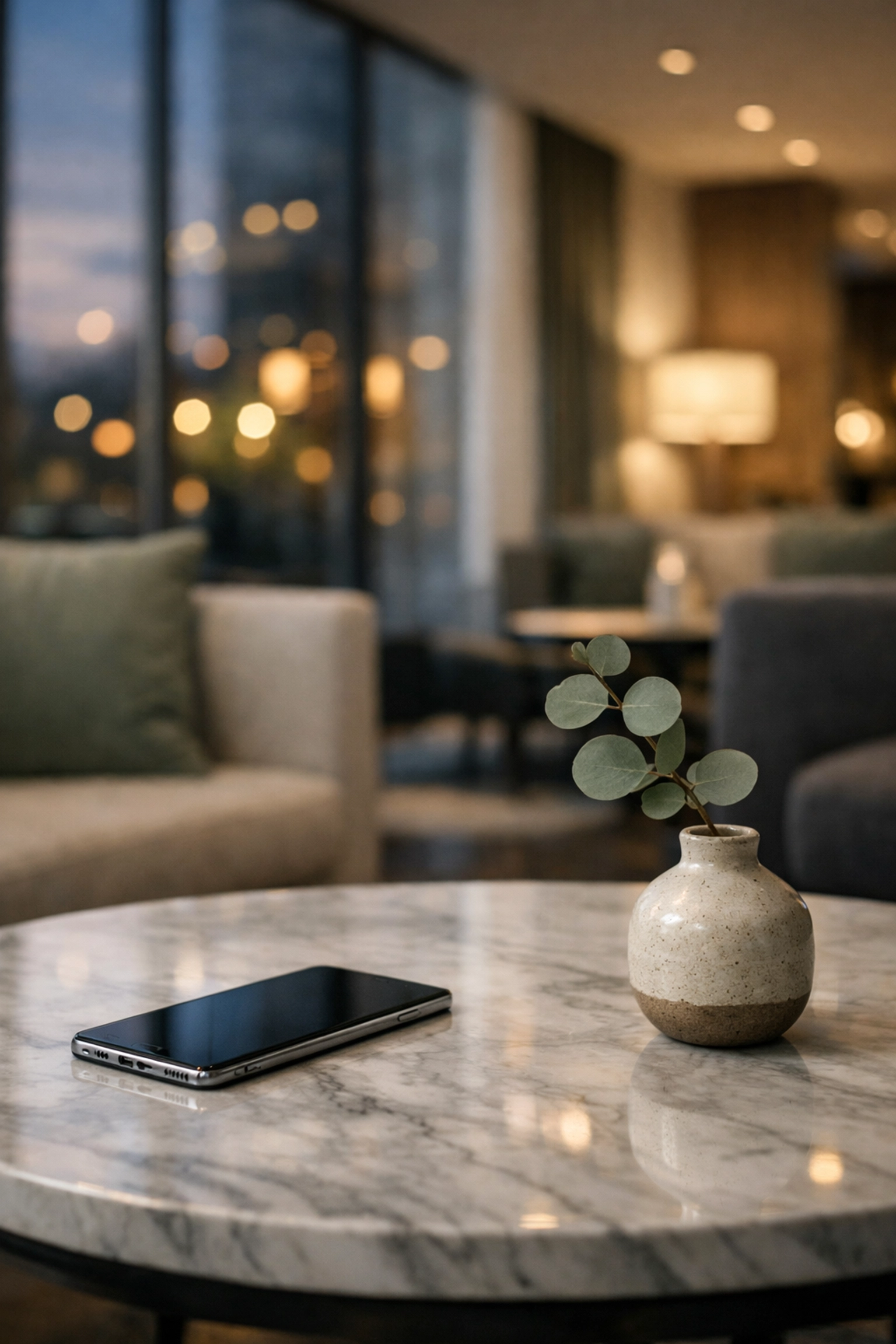A smartphone in a minimalist hotel lobby representing a cloud-native hotel PMS and connected data foundation.