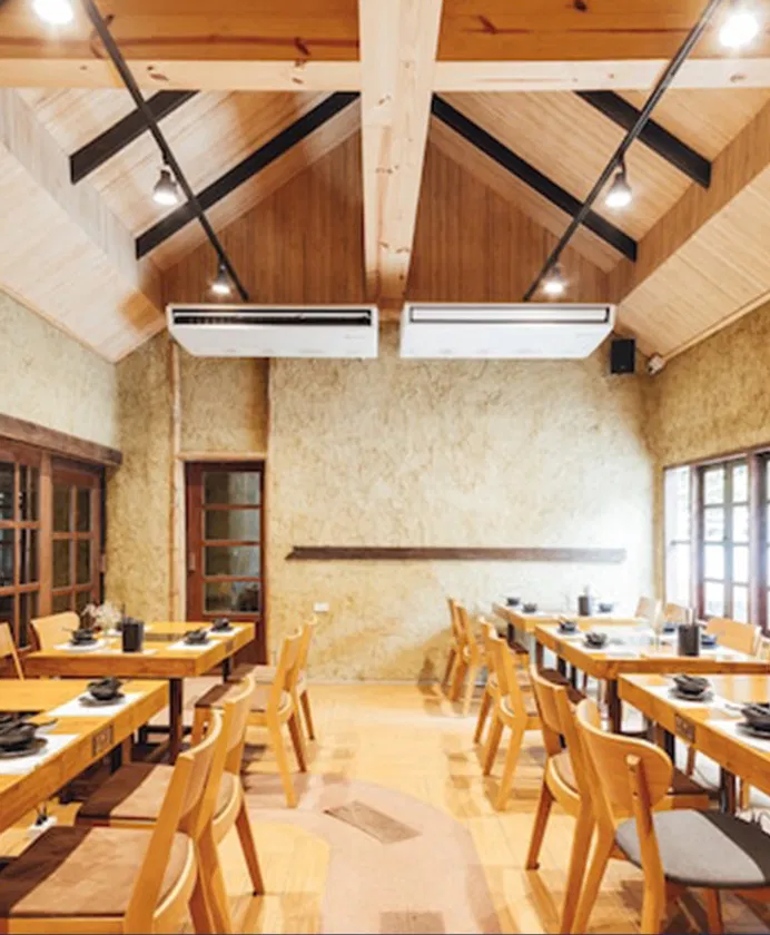 Inviting, modern restaurant interior with wooden vaulted ceilings and natural light, featuring neatly arranged tables and chairs.