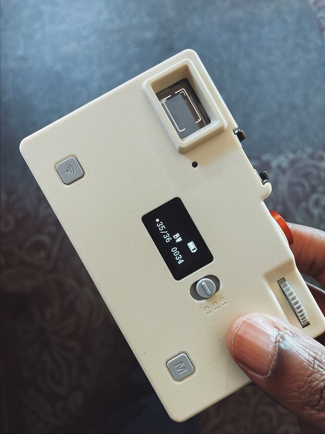 A close-up of a minimalistic, retro-inspired digital camera held in hand