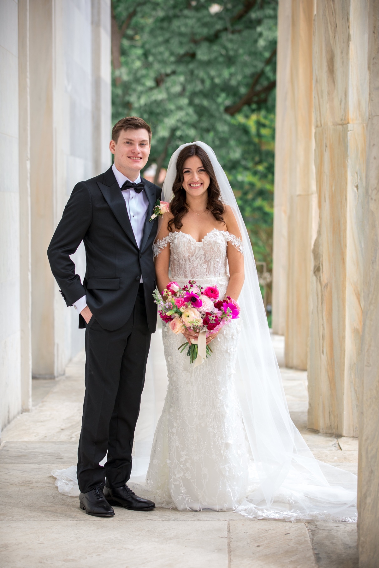 Bride and groom standing together in a marble colonnade