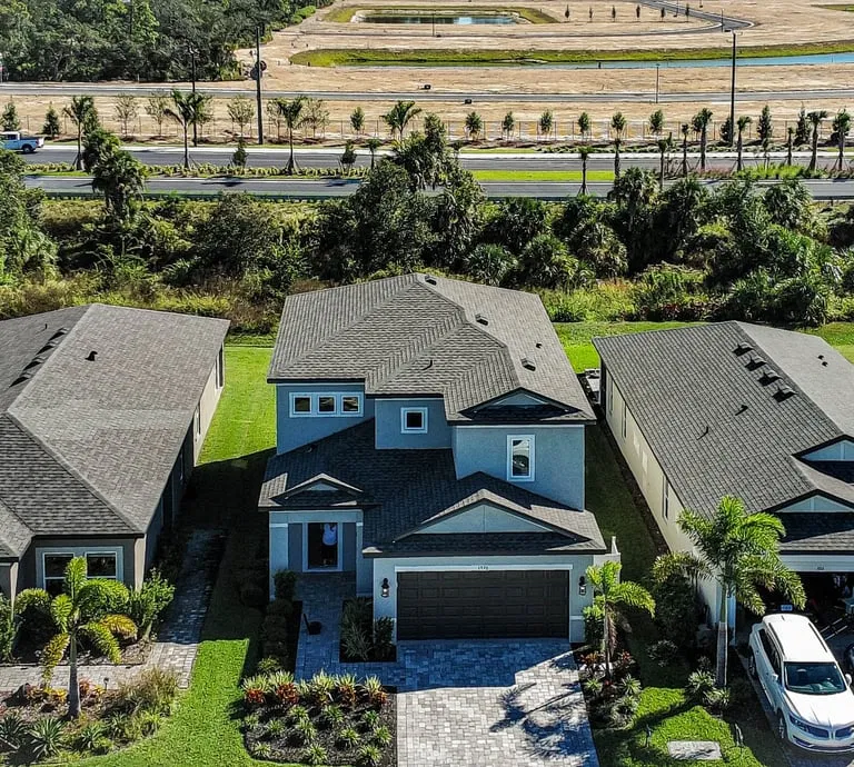High-resolution aerial image of a modern two-story home and neighboring properties, highlighting property features and landscaping