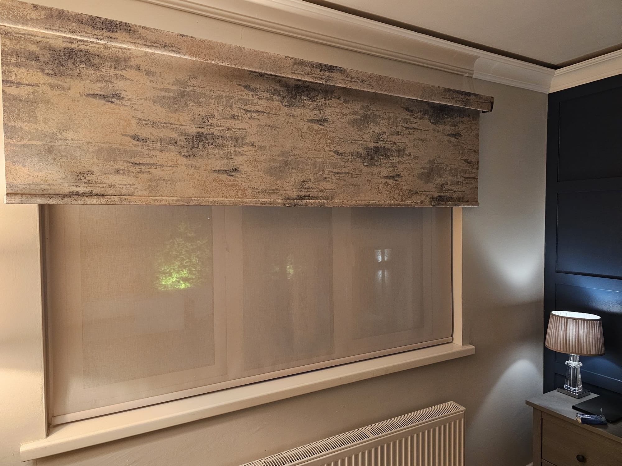 Modern living room window fitted with a bespoke roller blind featuring a textured, patterned fascia.