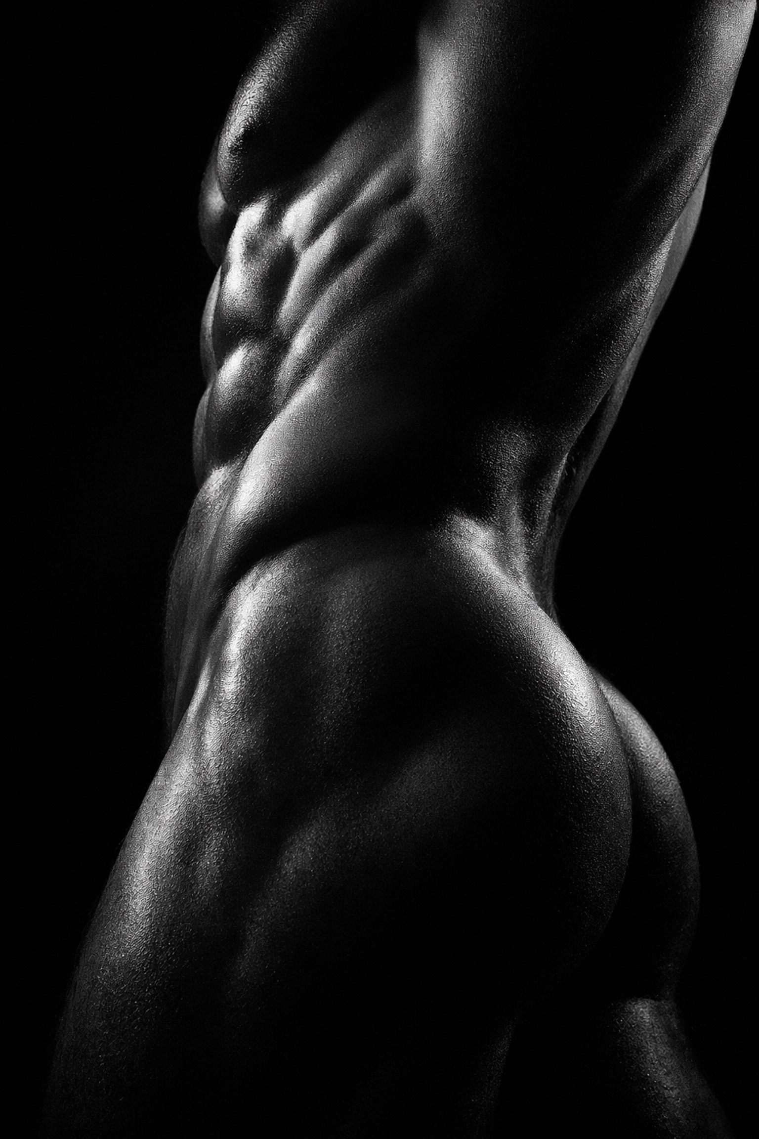 Artistic black and white photo of a muscular man’s torso and hips, capturing the geometry of the male body.