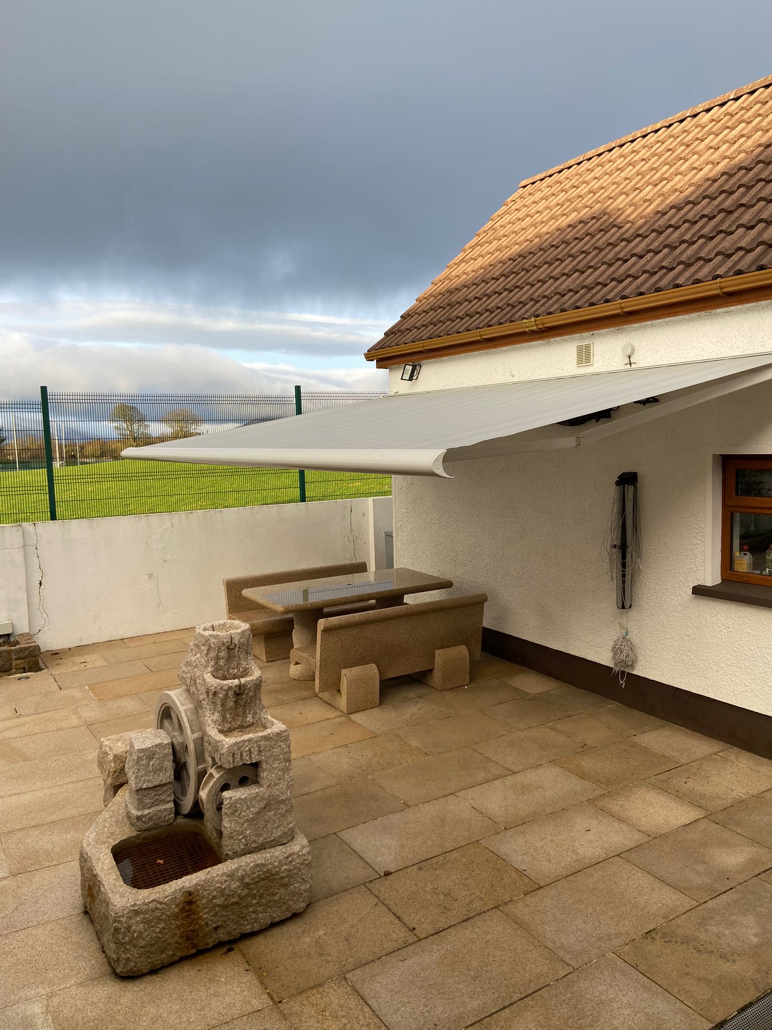 A modern motorised outdoor awning by Fiesta Blinds providing weather protection for a garden patio