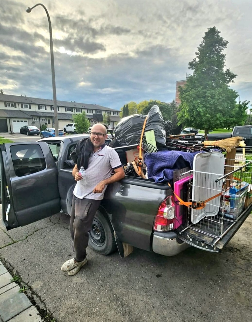 How to Get Rid of an Old Mattress in Innisfil: (Without the Headache) A Junk GTA crew member stands beside a pickup truck loaded with various junk items, prepared for responsible disposal.