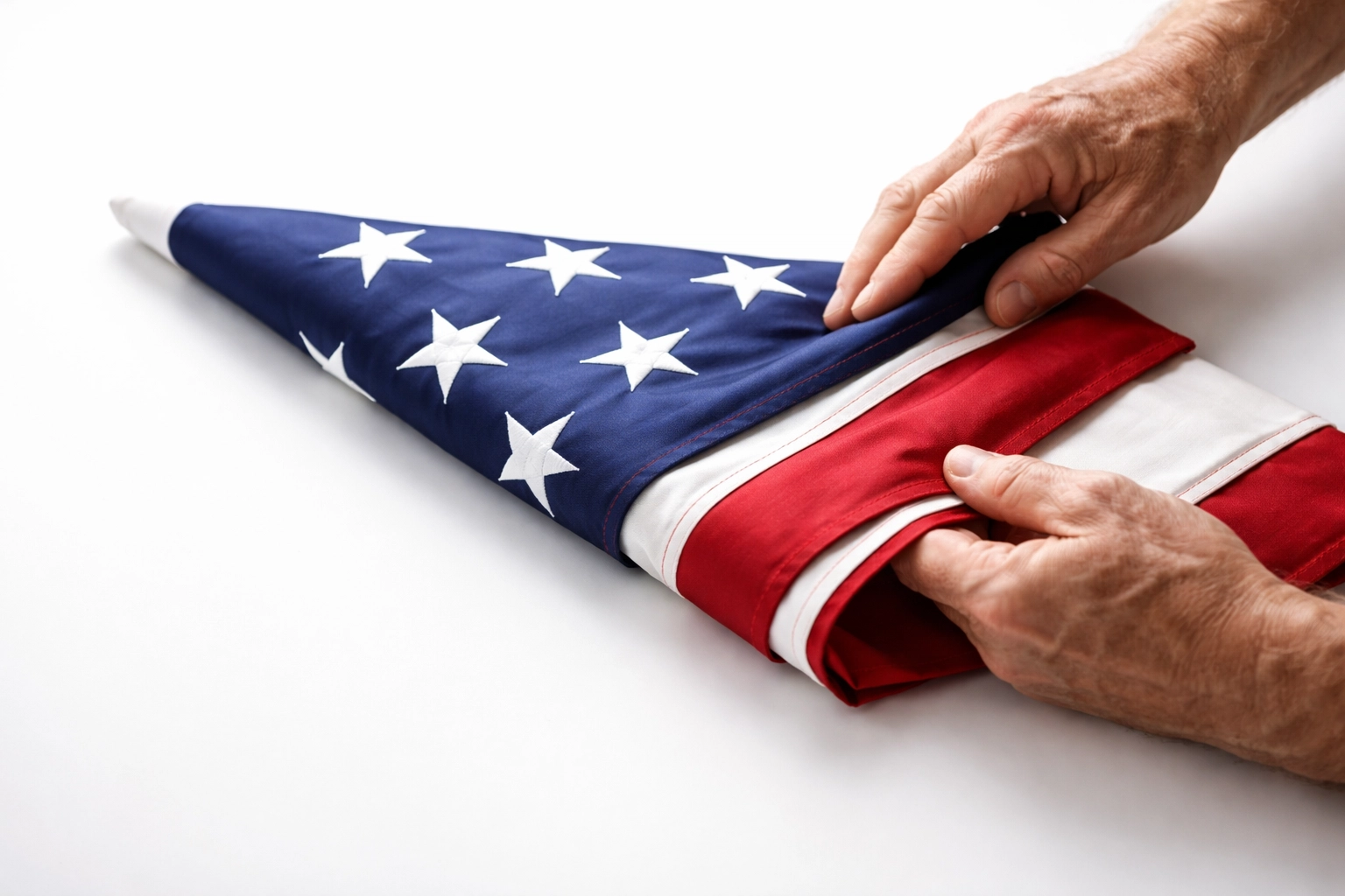 Hands folding an American flag into a triangle, demonstrating proper flag retirement etiquette