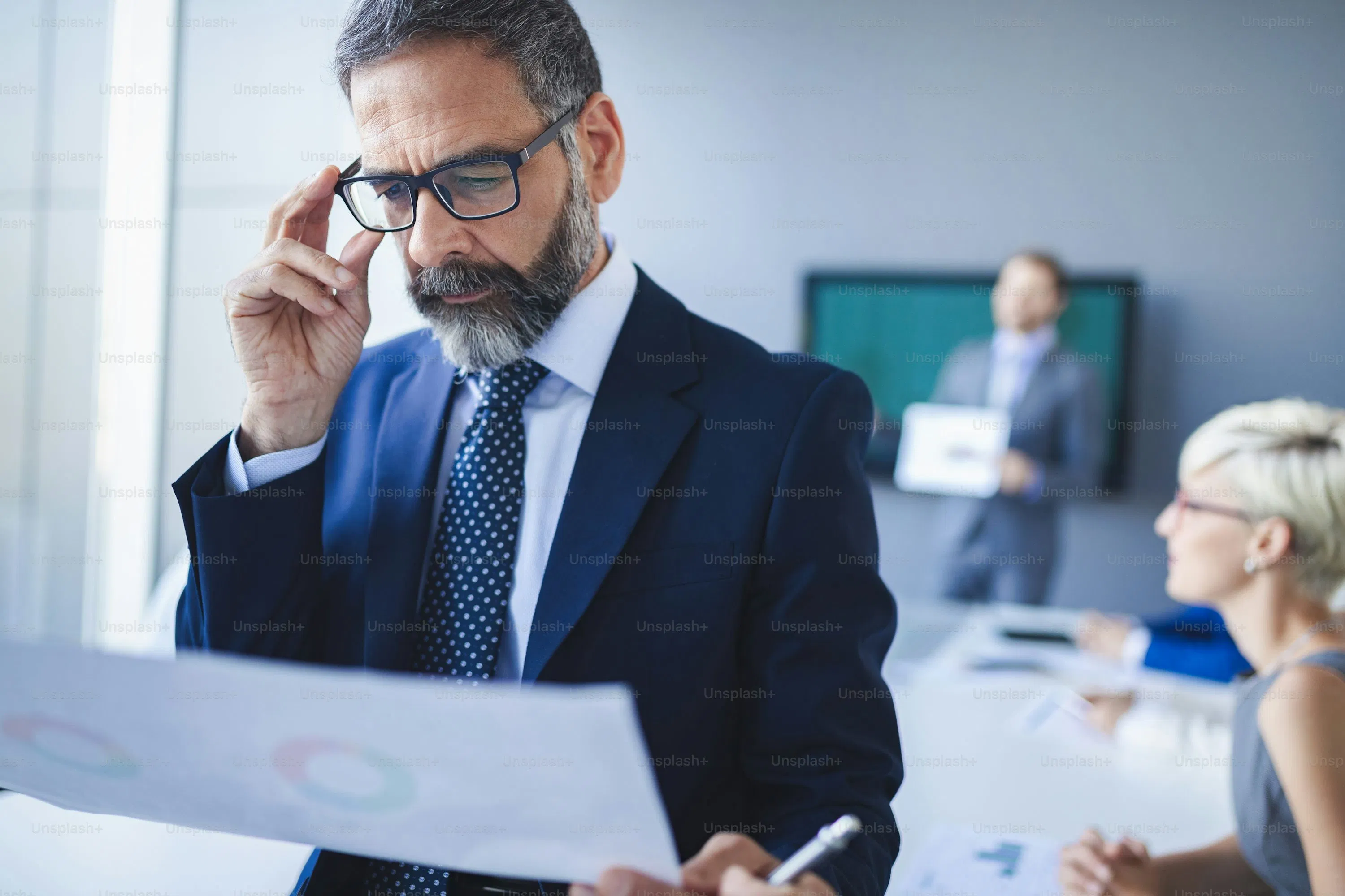A business professional closely reviewing financial reports during a meeting