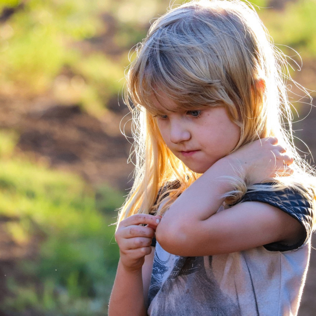 Child rubbing neck outdoors