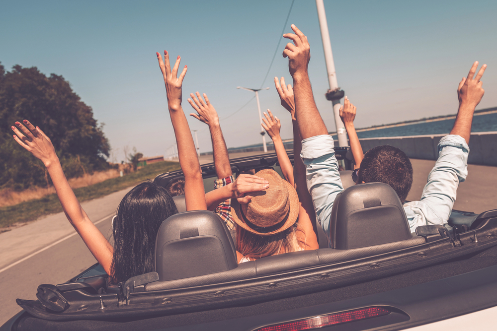 A group of young adults riding together in a convertible