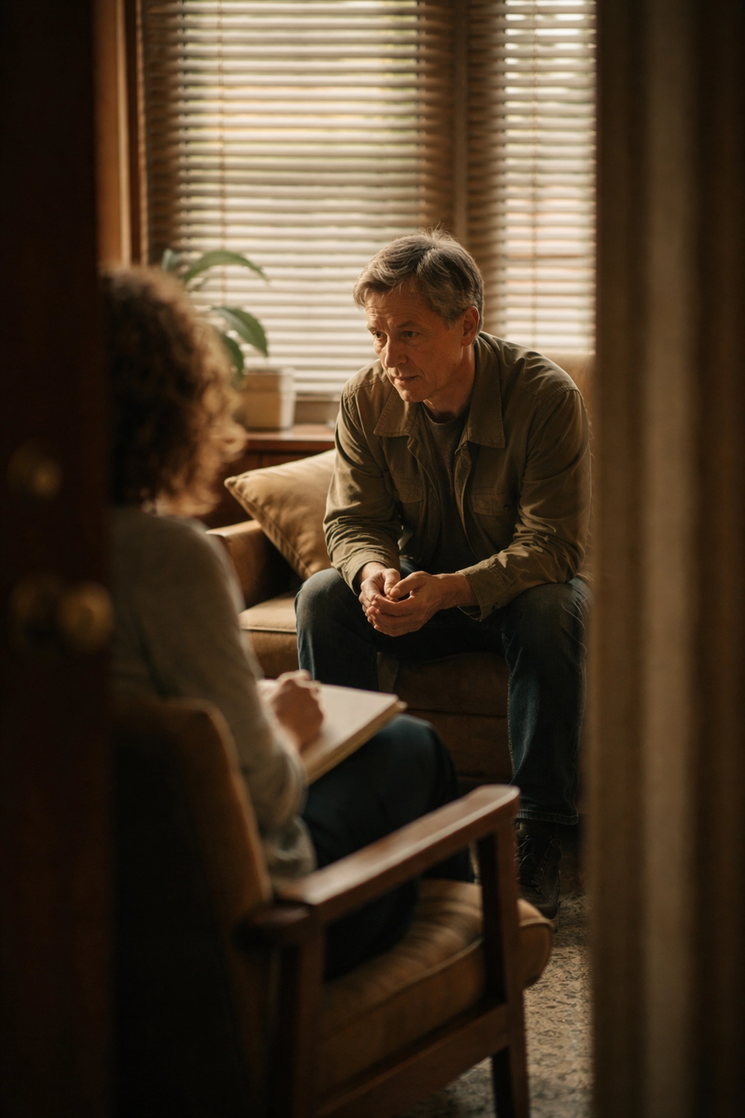 Person meeting with a therapist in a softly lit room, highlighting the importance of professional help in family healing after addiction