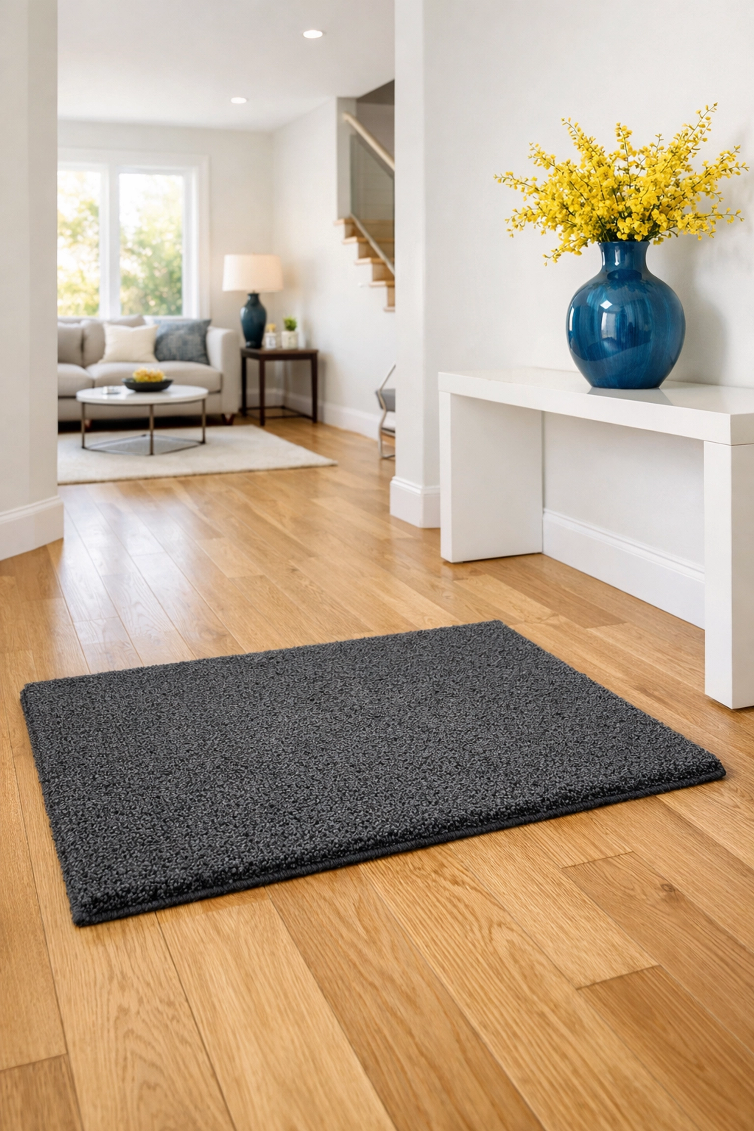 Charcoal grey doormat on light oak floors in a clean, modern home entrance foyer.