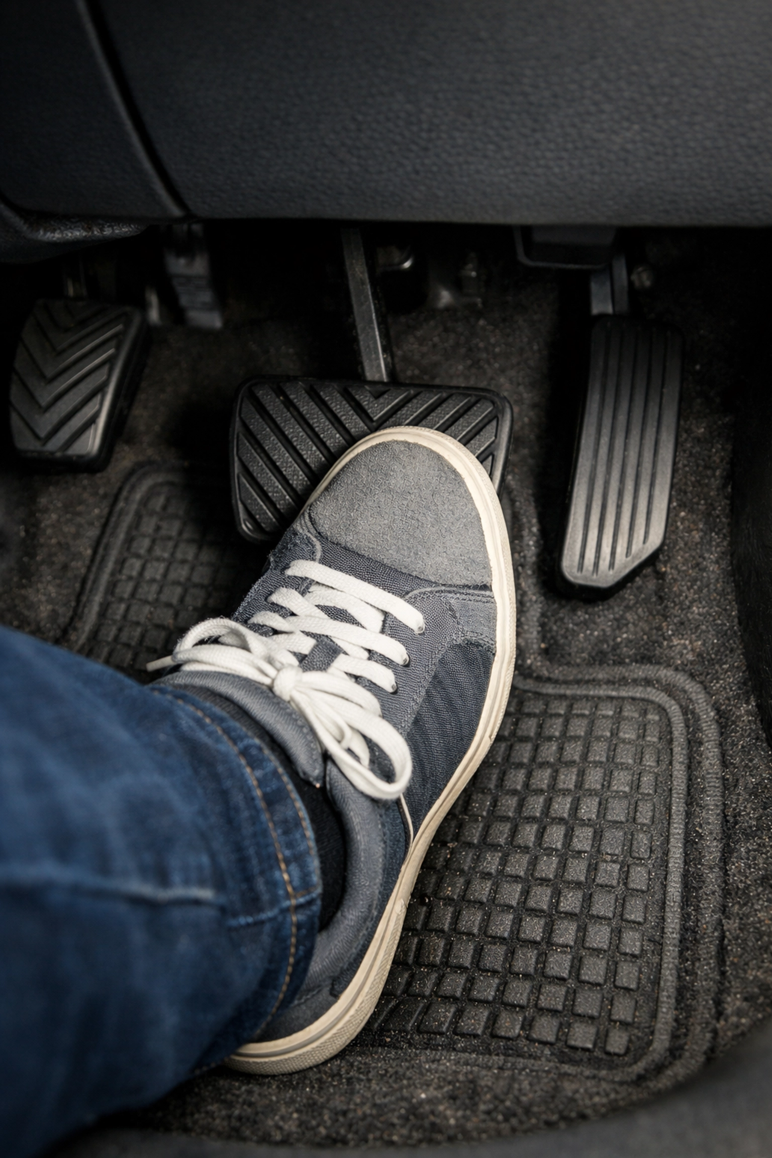 A driver pressing a spongy brake pedal to the floor, signaling a need for immediate brake service.