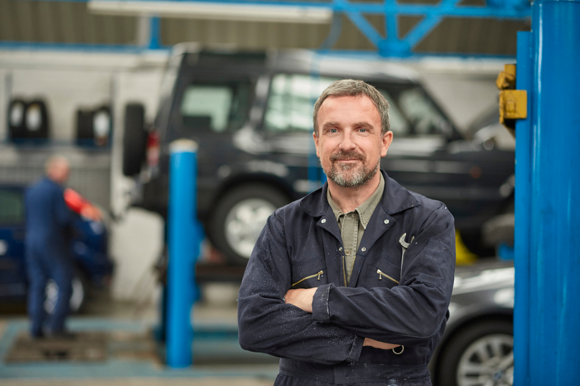 Auto Repair Shop Owner Portrait An auto repair shop owner stands confidently in the workshop, representing a local service business ready for digital transformation with HighLevel Automation Lab's end-to-end automation, CRM, and workflow solutions.