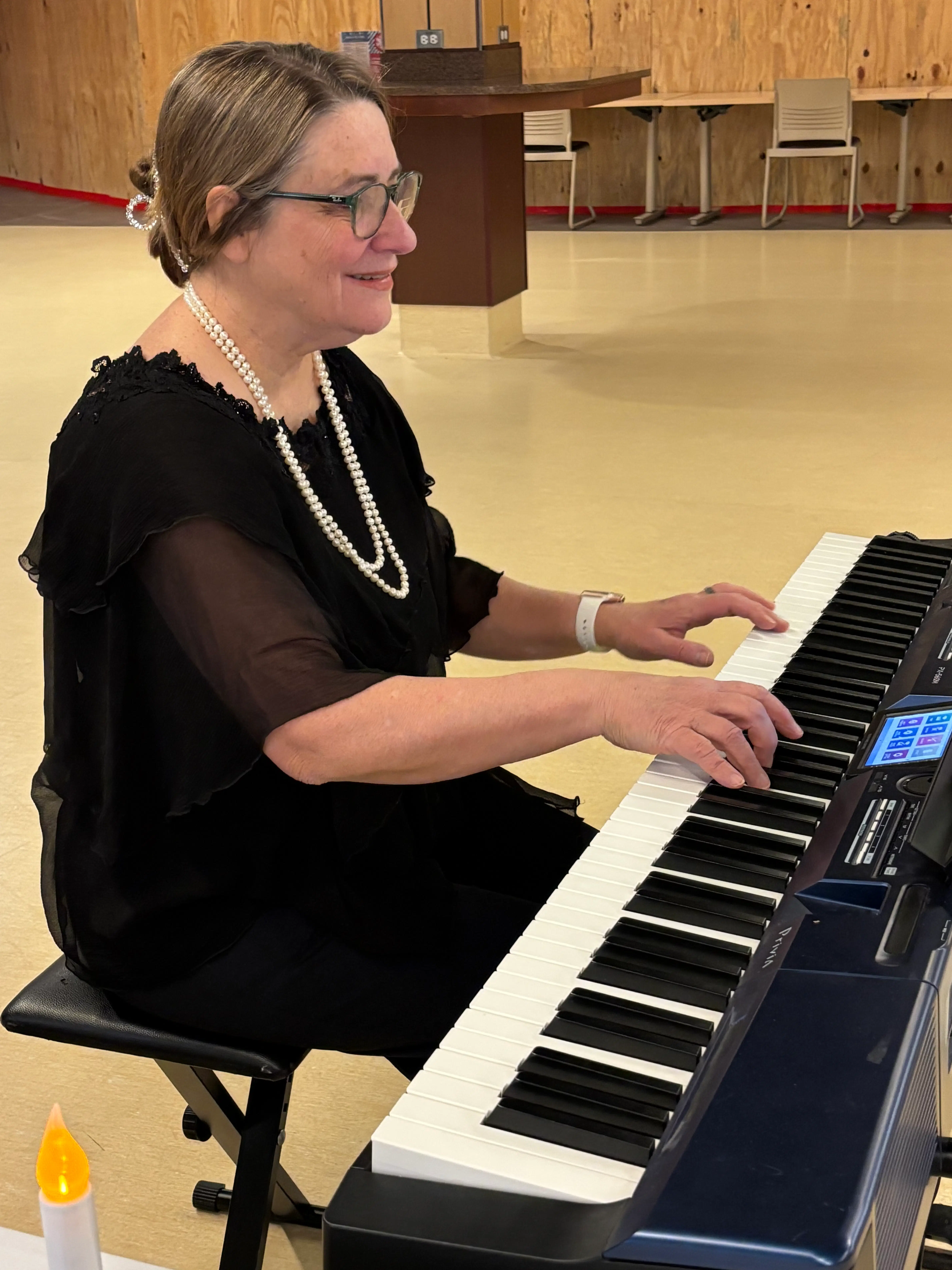 An elegantly dressed woman playing a digital piano in a relaxed setting
