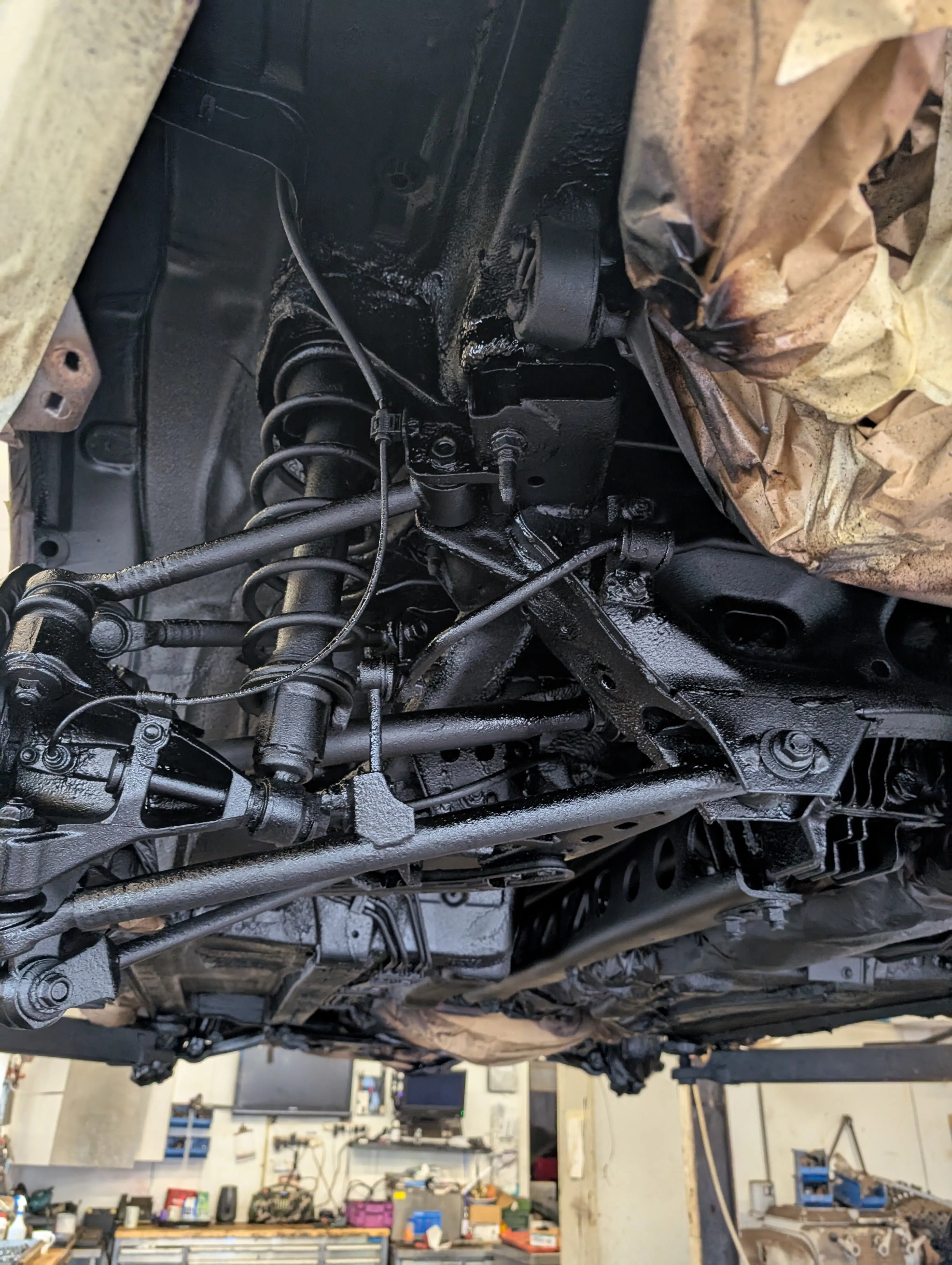 Close-up of freshly applied rust proofing treatment on suspension and frame components showing 'creep'