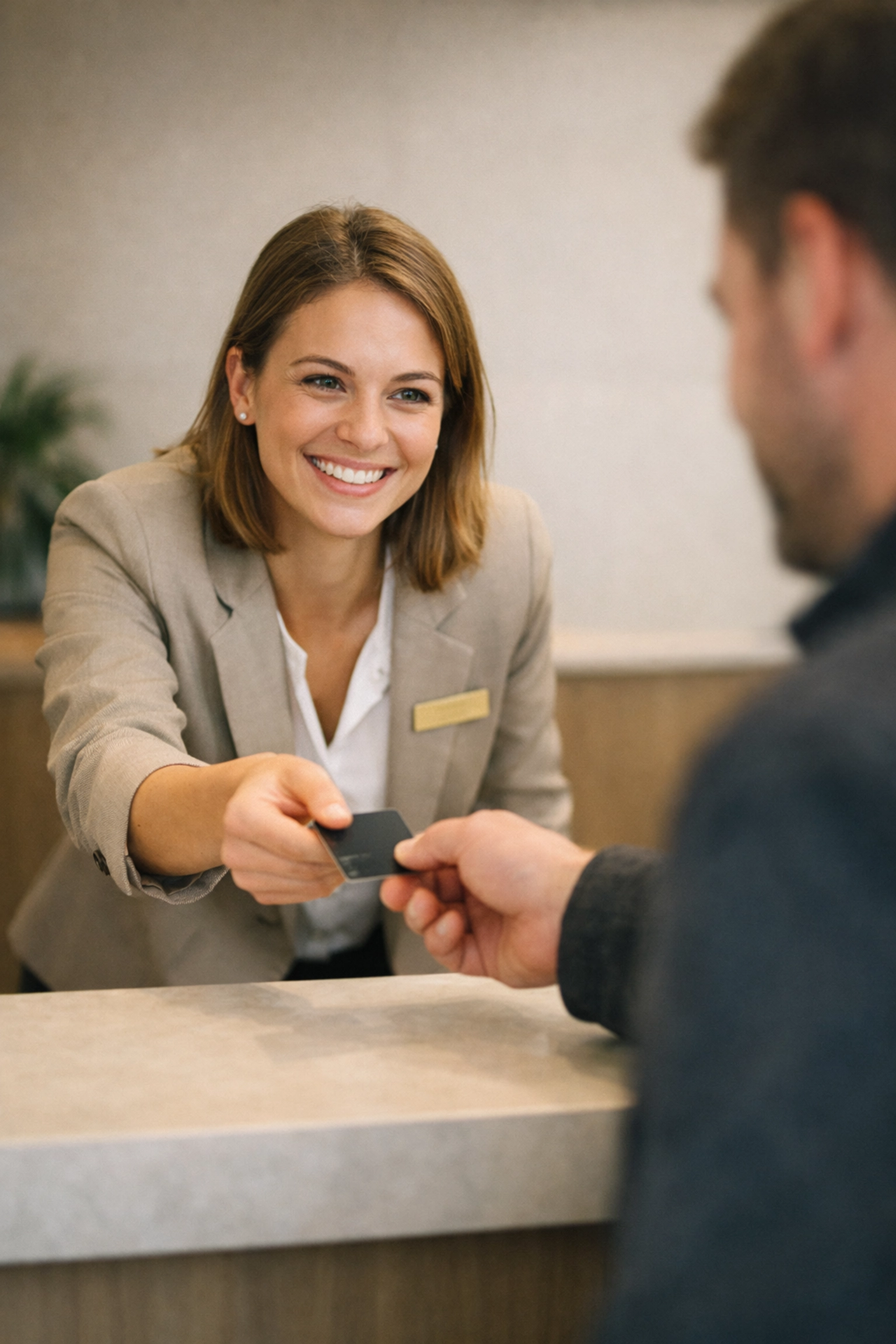 Hotel front desk staff handing a room keycard to a guest after a quick automated check-in.