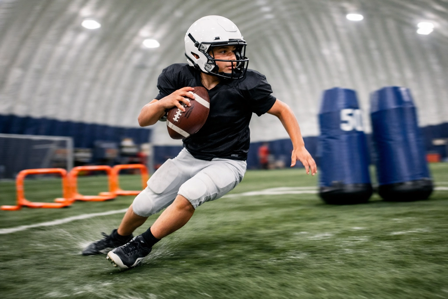 Youth QB scrambling during dynamic L.E.A.D. training drills at an indoor football turf facility.