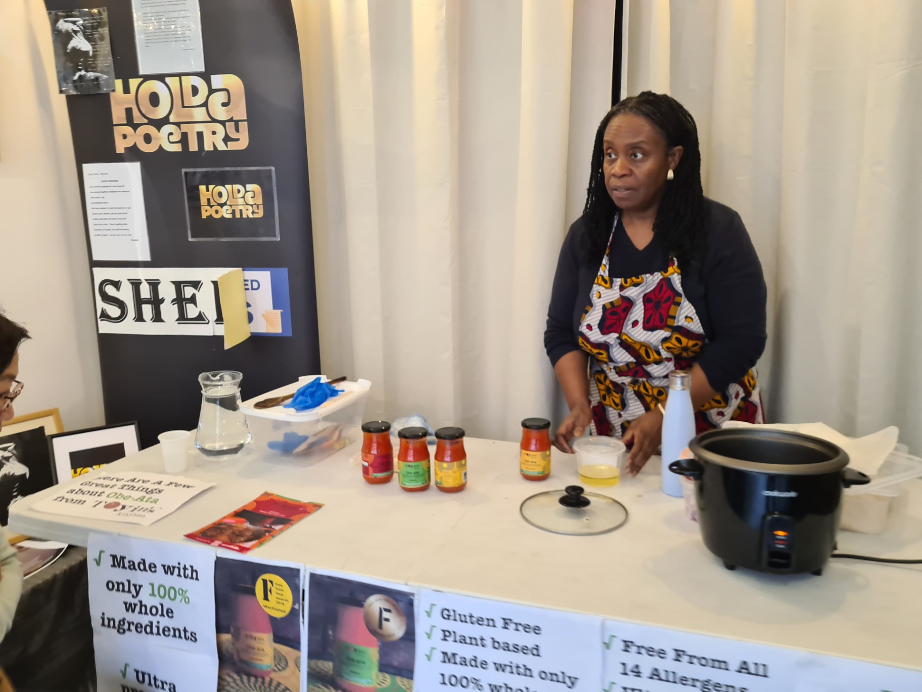 [HERO] Toyin’s Kitchen in Hammersmith: Toyin behind the stall with Obé-Ata plant-based cooking sauces (free from 14 allergens)