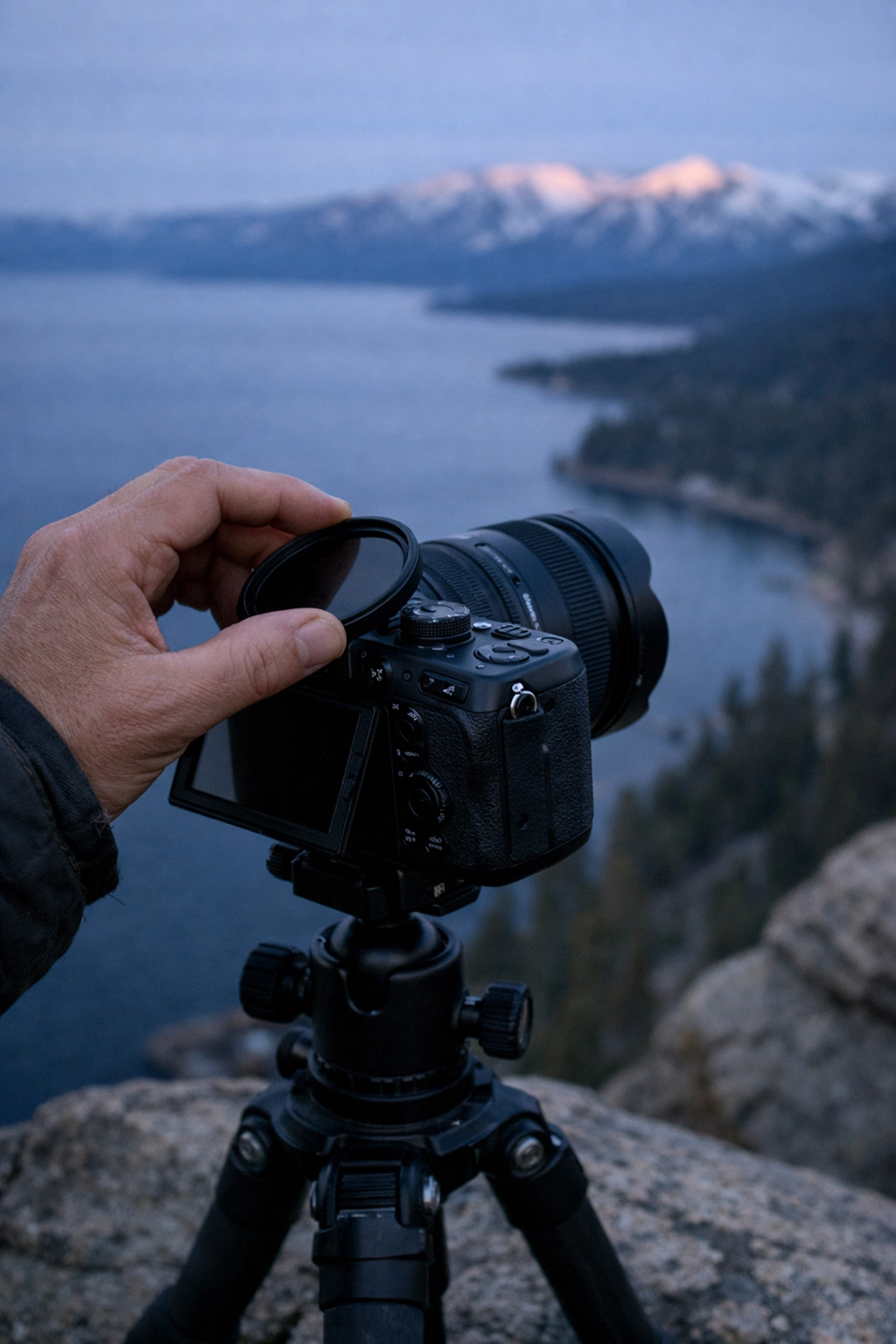 Professional camera setup on a cliff edge overlooking Lake Tahoe during blue hour photography.