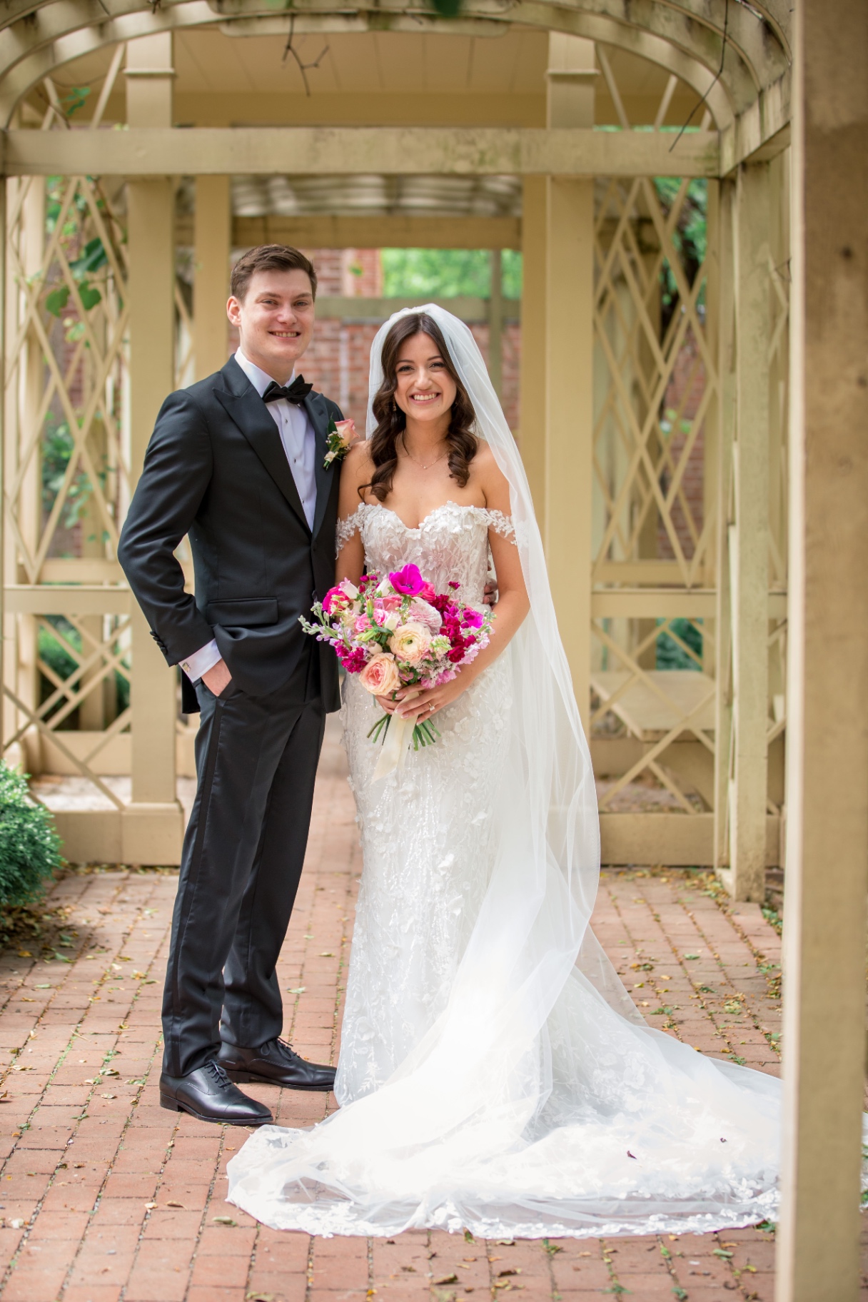 Leighanna and Brian beneath a light-filled arbor—smiling like the whole future is waiting