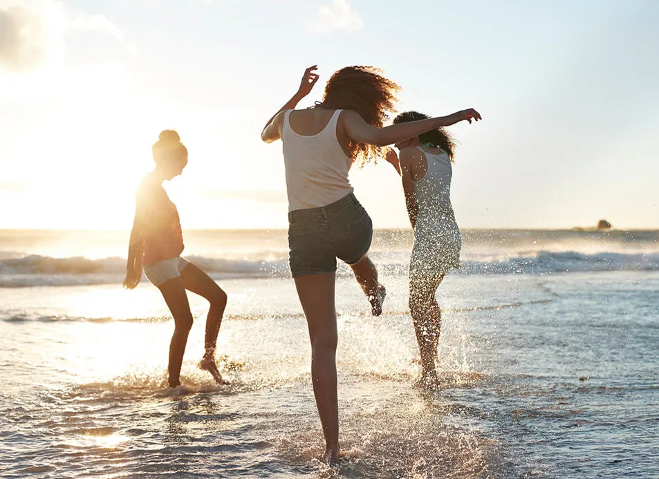 three-women-splashing-ocean-sunset-joyful-freedom.webp