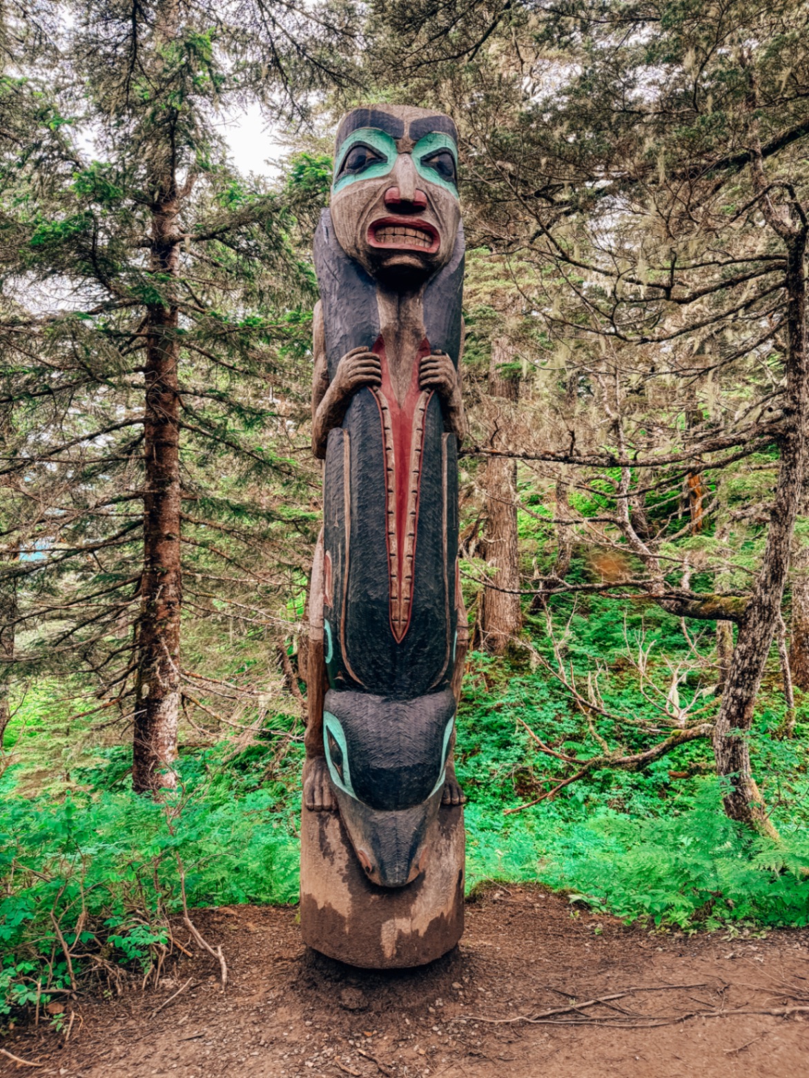 A traditional Native Alaskan totem pole standing in the forest