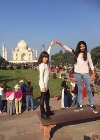A mother and daughter sharing a joyful, playful moment at the Taj Mahal, capturing the essence of shared exploration.