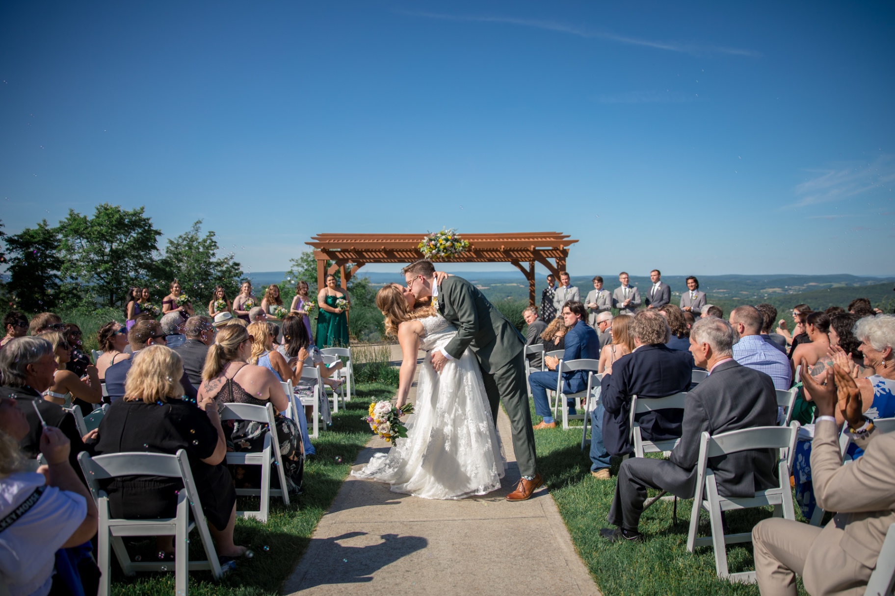 Bride and groom share a kiss at the end of an outdoor wedding ceremony