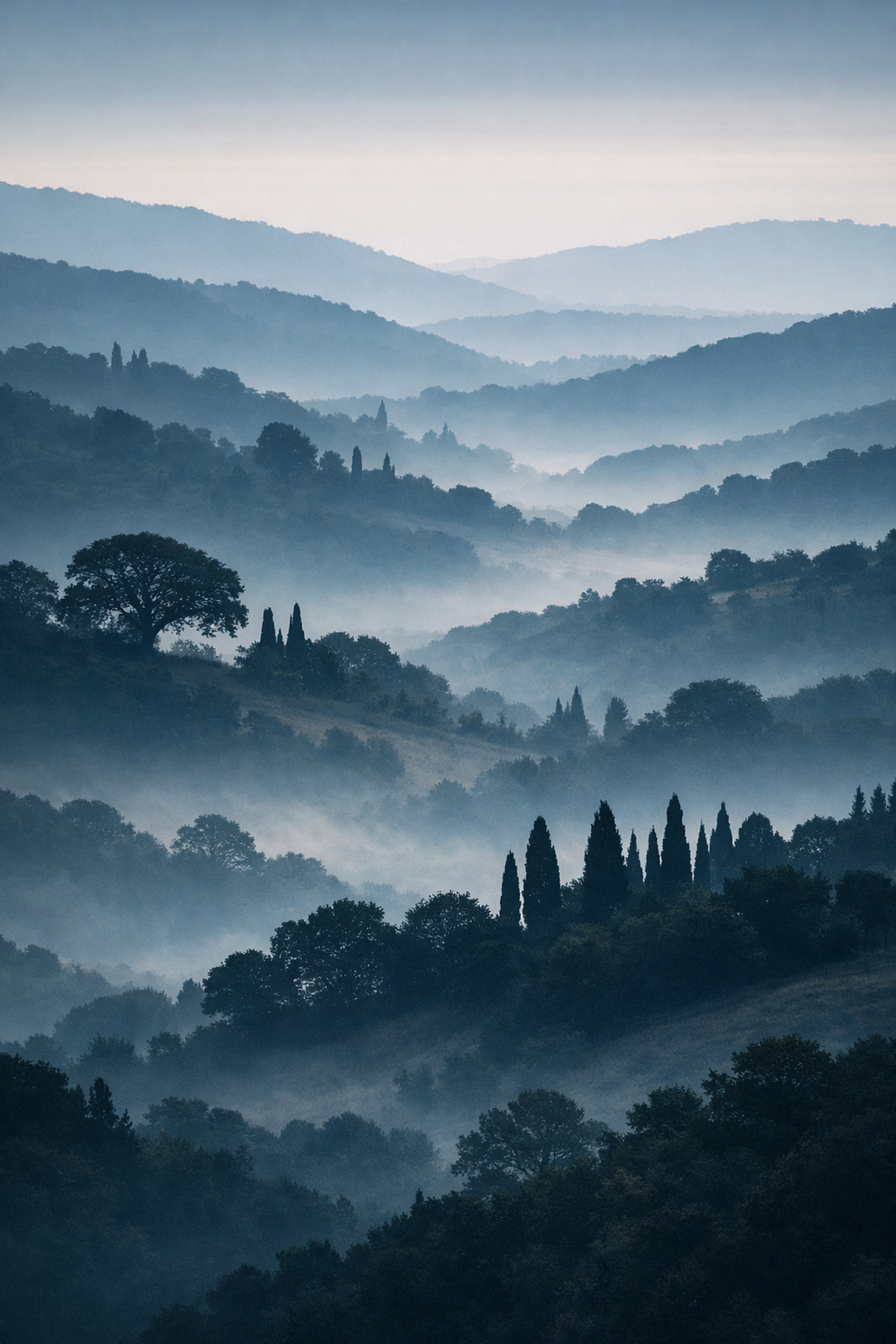 Telephoto landscape photography of misty rolling hills showing lens compression and layered ridges at dawn.