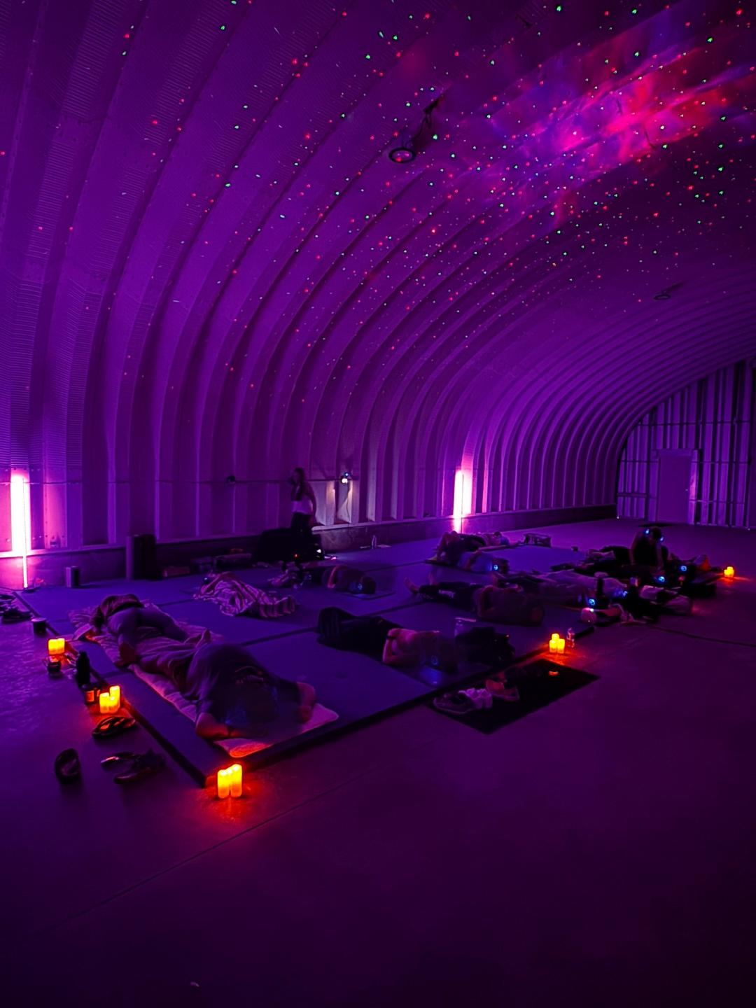 9D Breathwork Session at Vero Beach Aura Participants are lying on mats in a dimly lit, purple-illuminated space