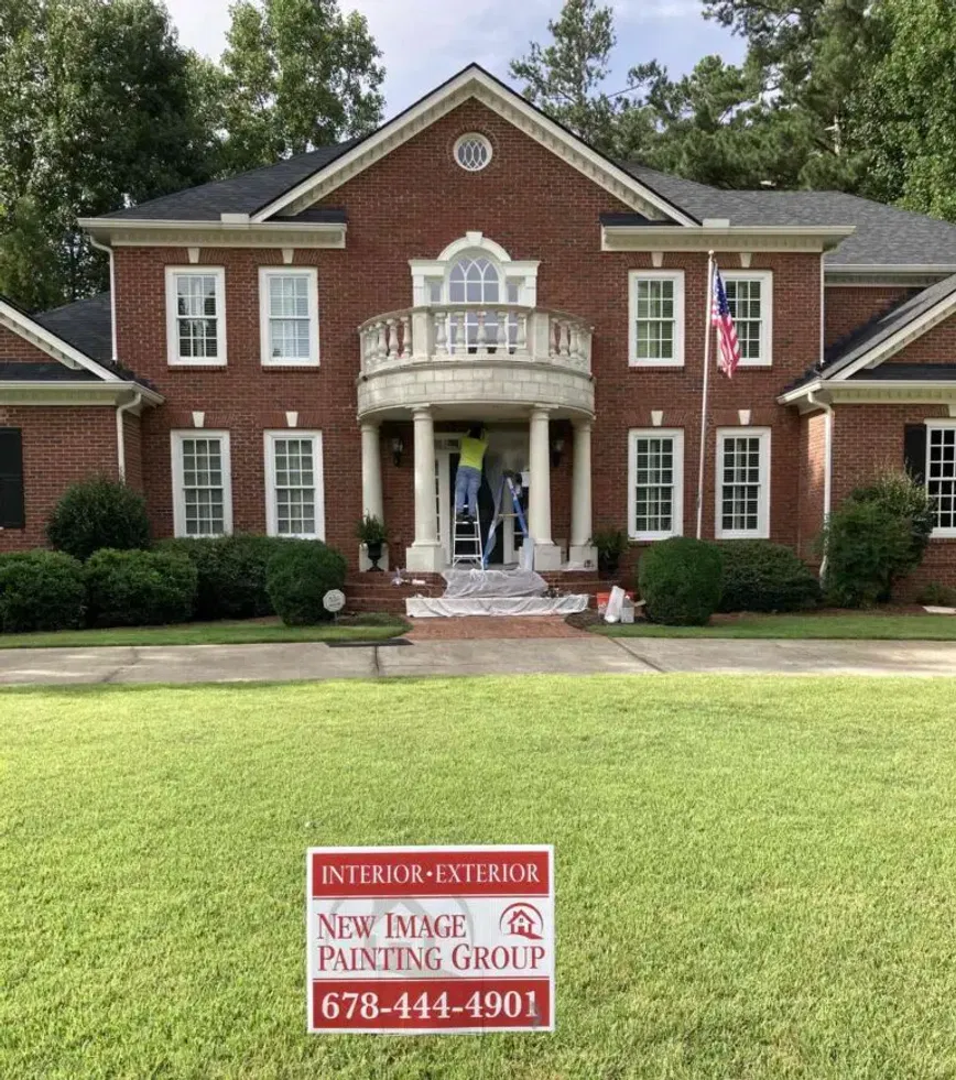 Professional exterior painting on a brick home with New Image signage