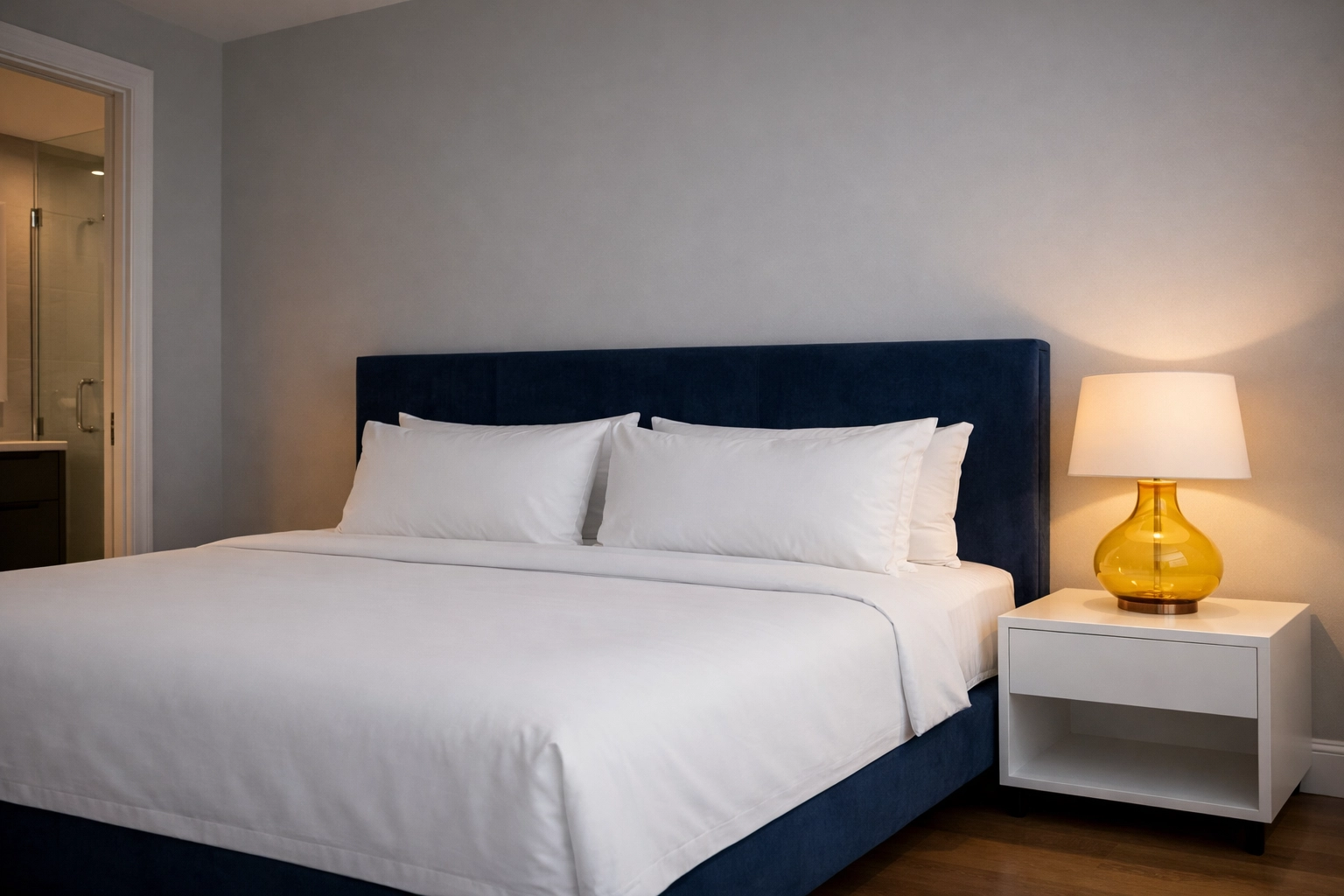 A pristine, minimalist bedroom suite in Needham with expert bedding and luxury residential cleaning details.