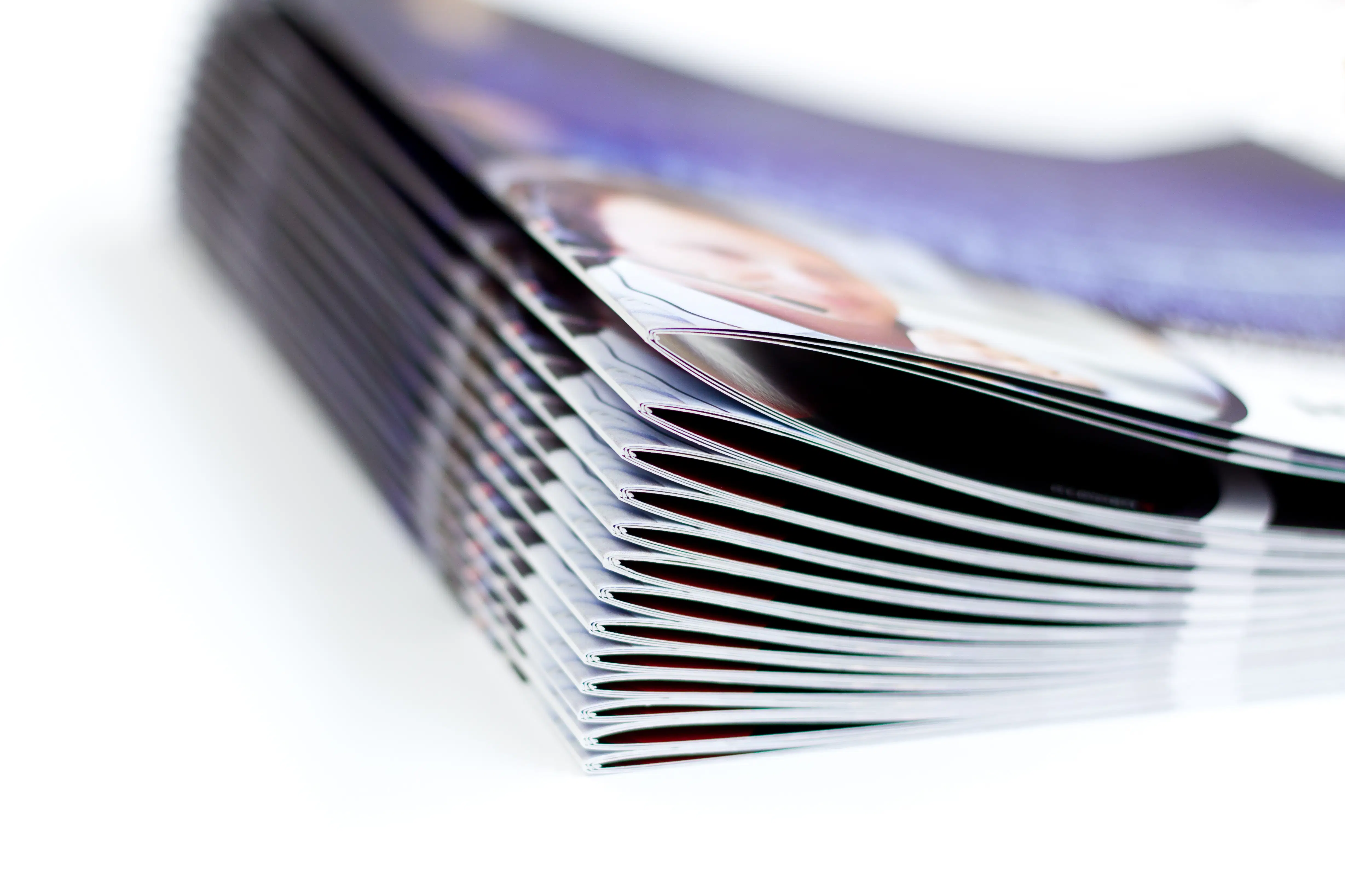 Close-up stack of professionally finished, saddle-stitched booklets with glossy covers.