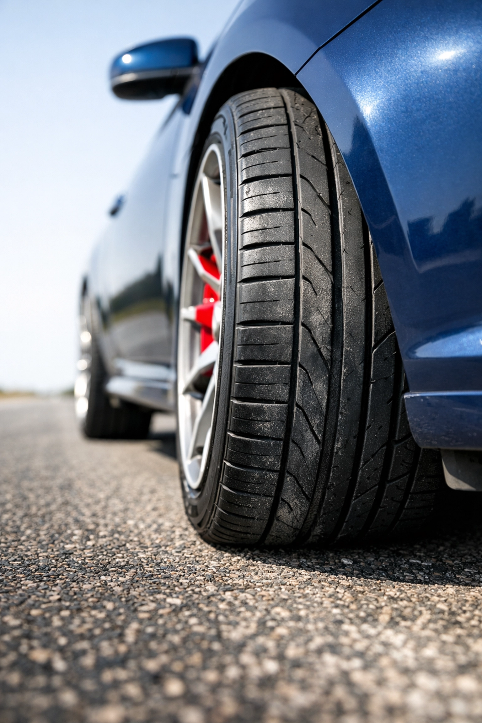 Close-up of a vehicle tire with uneven tread wear on Texas asphalt due to poor wheel alignment.