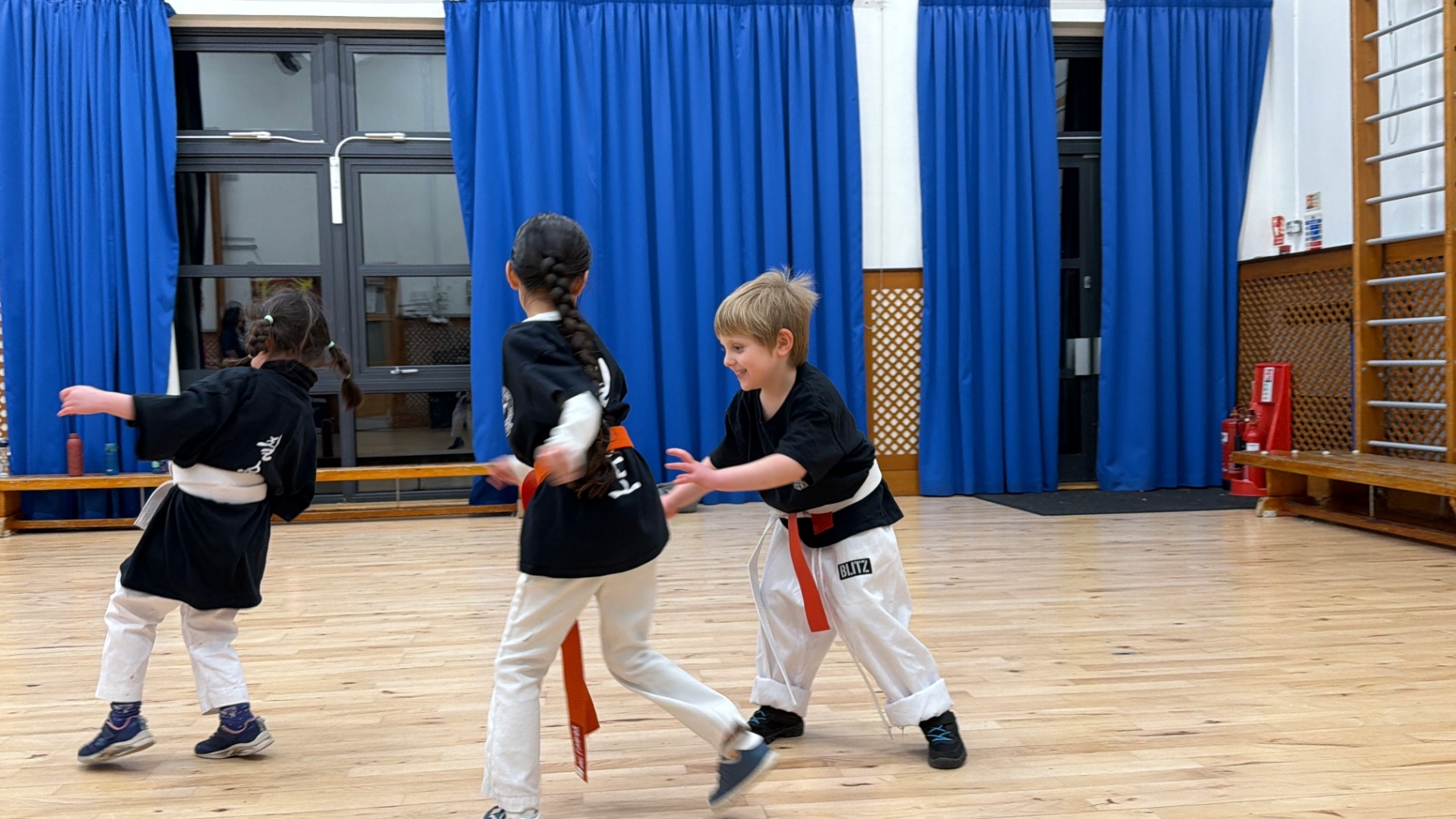 Three young children in martial arts uniforms