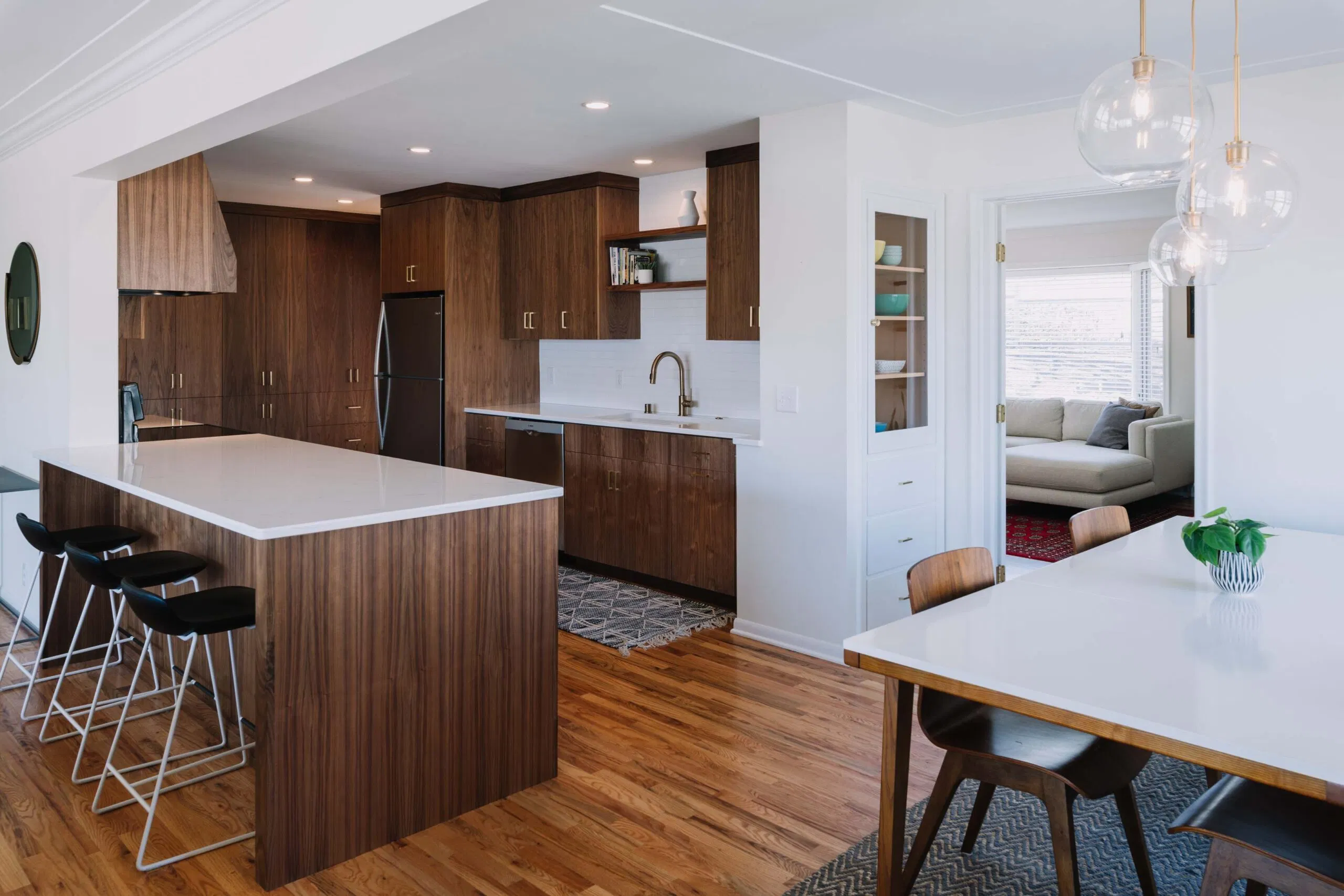 Modern kitchen and dining space featuring custom American walnut cabinetry and large waterfall-edge island