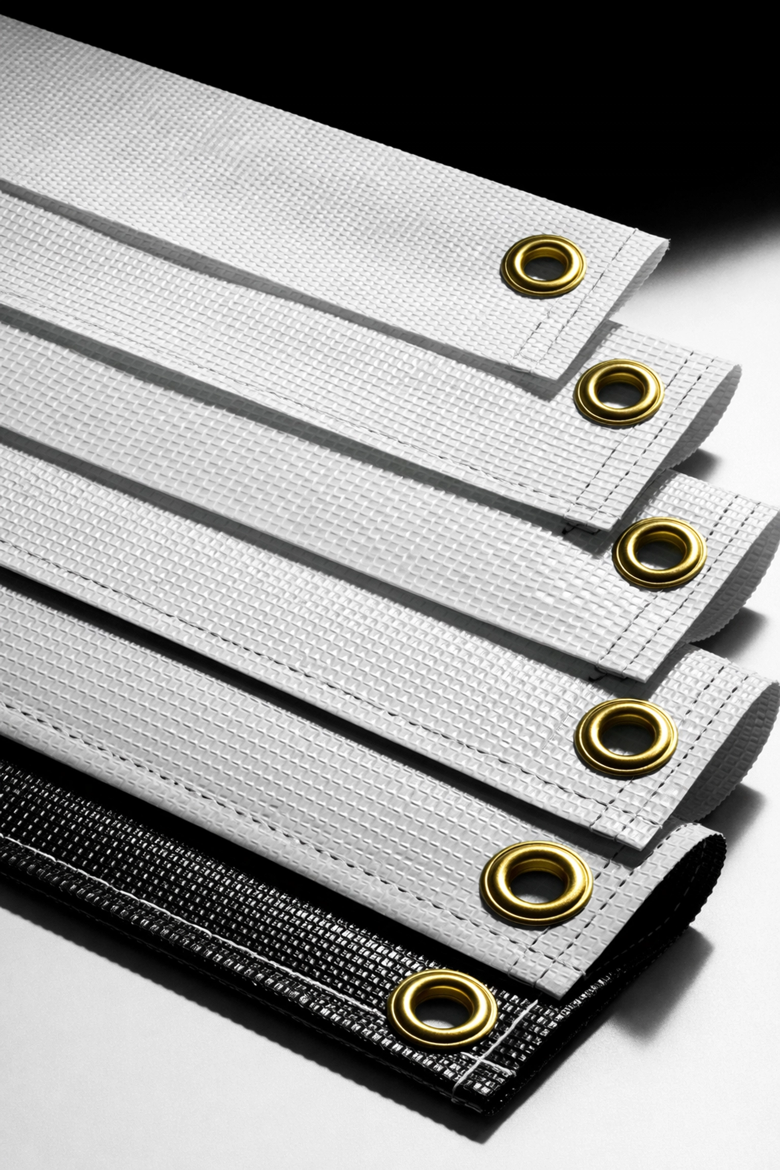 Multiple scrim vinyl banner samples showing different weights and grommet options