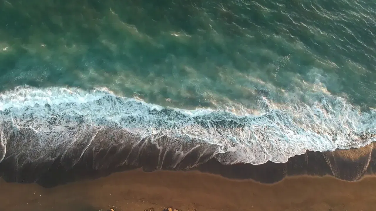 Aerial view of waves gently meeting the shore, symbolizing smooth transitions and the next chapter for business owners