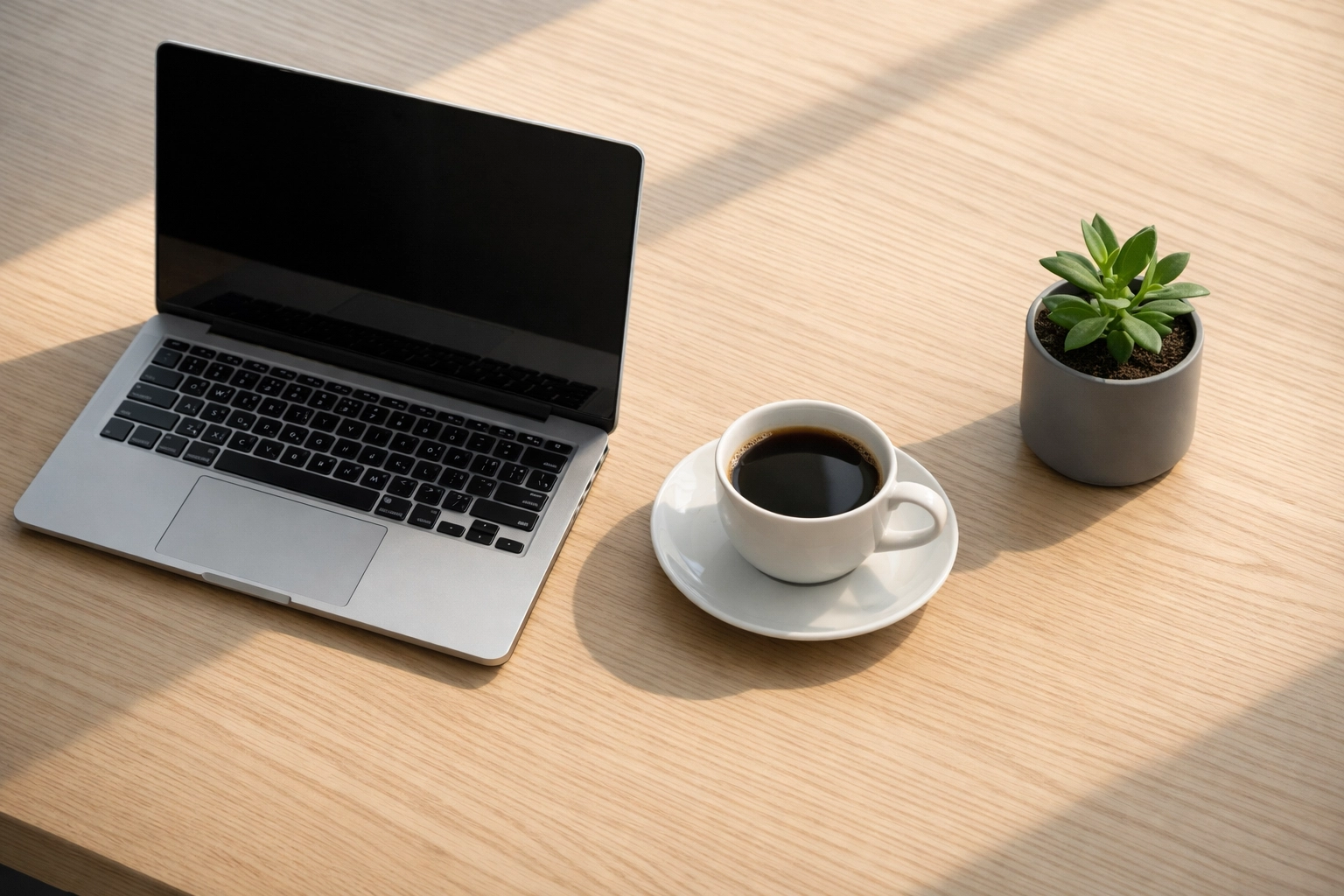 A minimalist hotel office desk with a laptop and coffee, symbolizing an efficient hospitality SEO workflow.