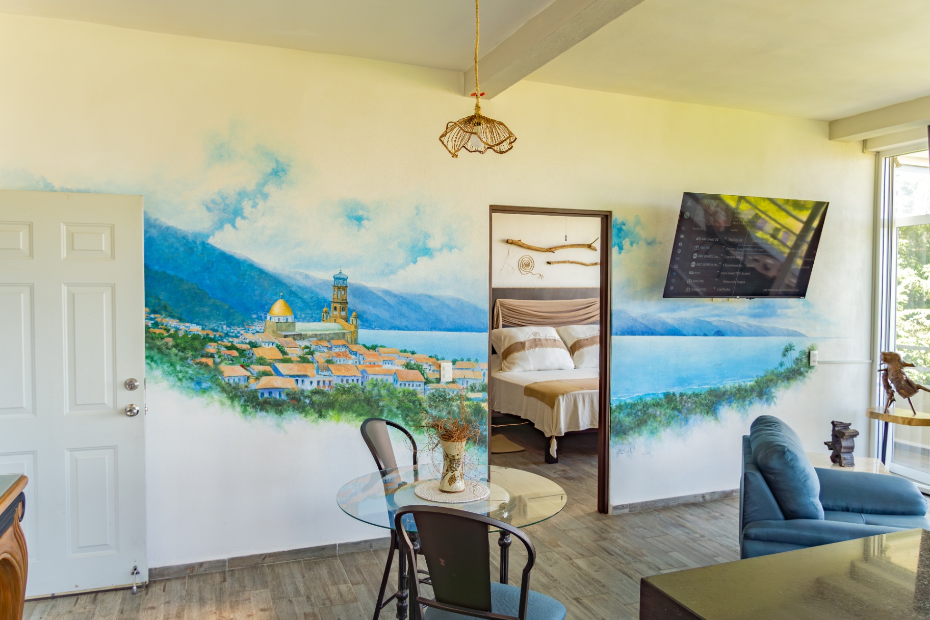 Open-plan condo interior with Puerto Vallarta mural and ocean view