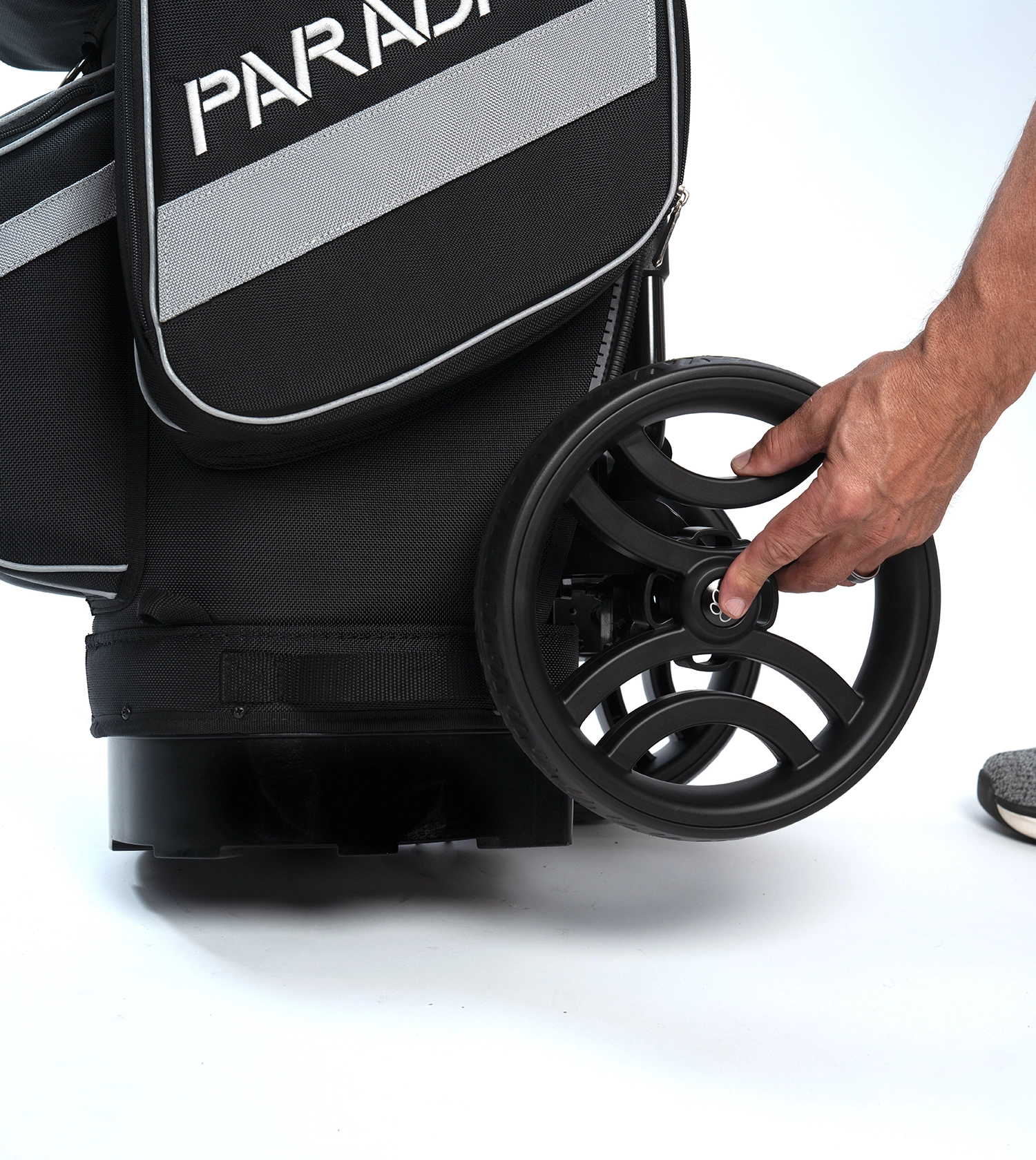 A close-up of the PARADAX AI-1 golf bag showing a hand easily attaching one of the wheels