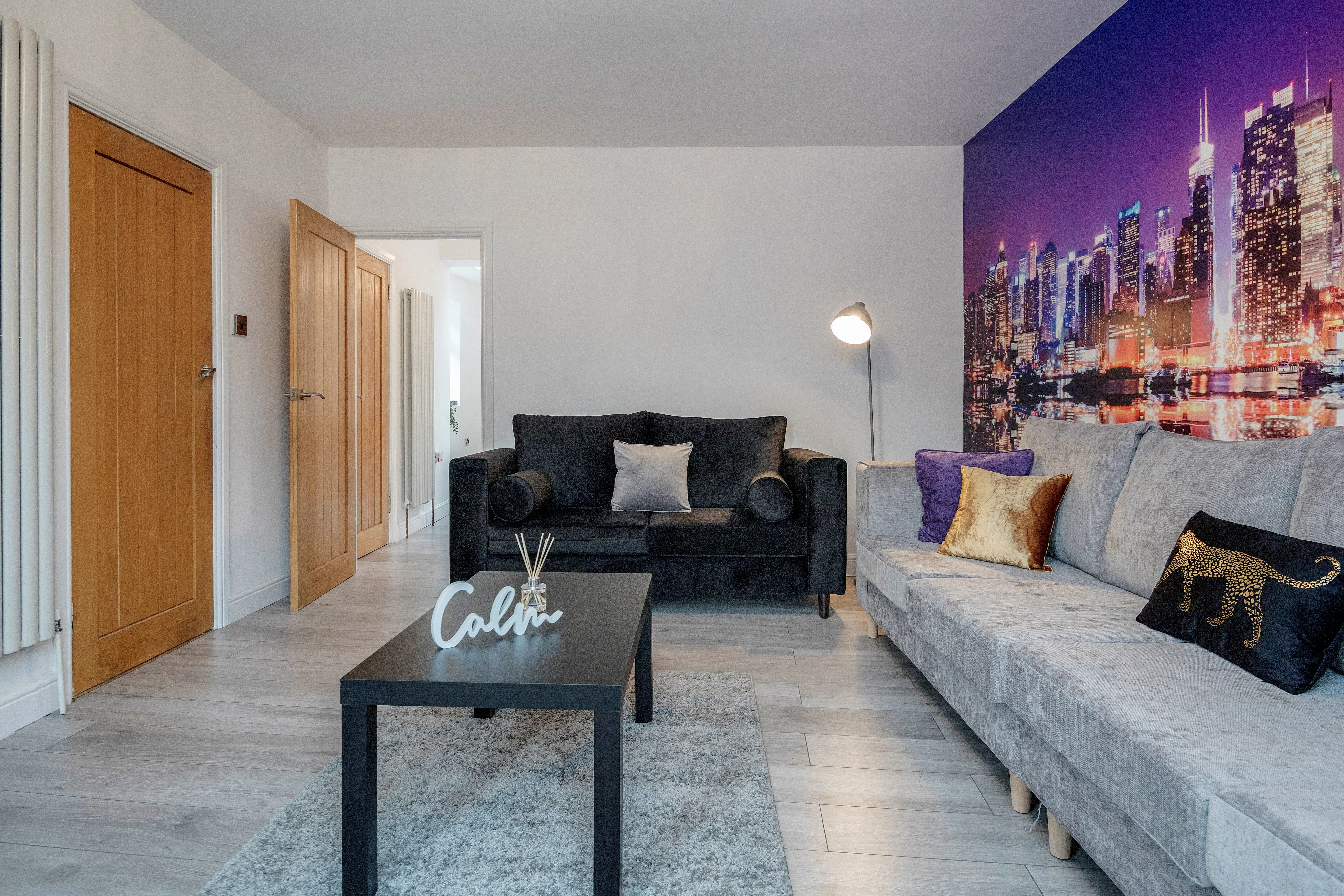 Cowridge House lounge with modern grey and black sofas and a colourful cityscape mural.