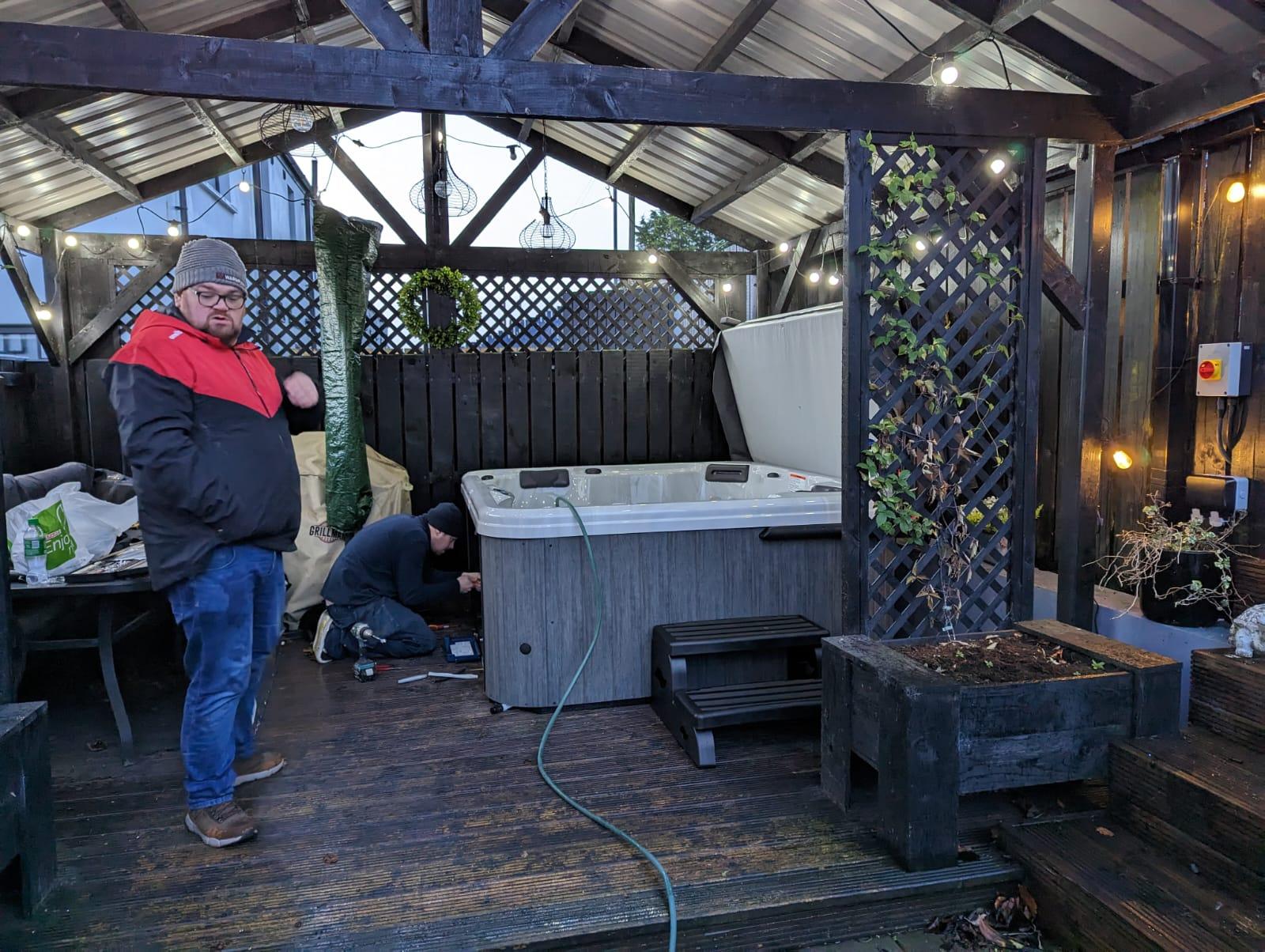 Fiesta Spas team installing a premium hot tub under a covered outdoor decking area