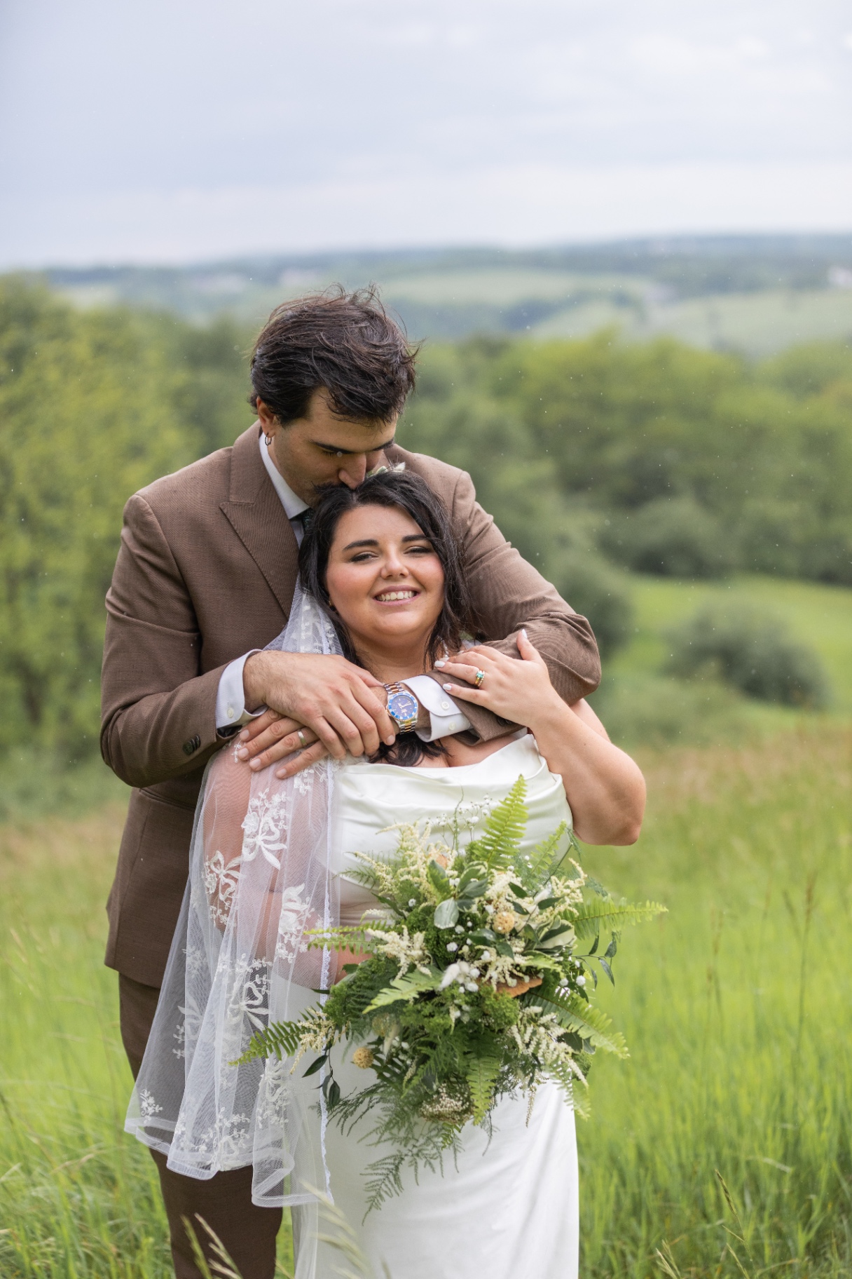 Bride and Groom Embracing in a Lush Green Field